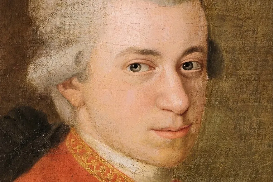 Close-up portrait painting of composer Wolfgang Amadeus Mozart in a powdered wig and red coat, looking forward.