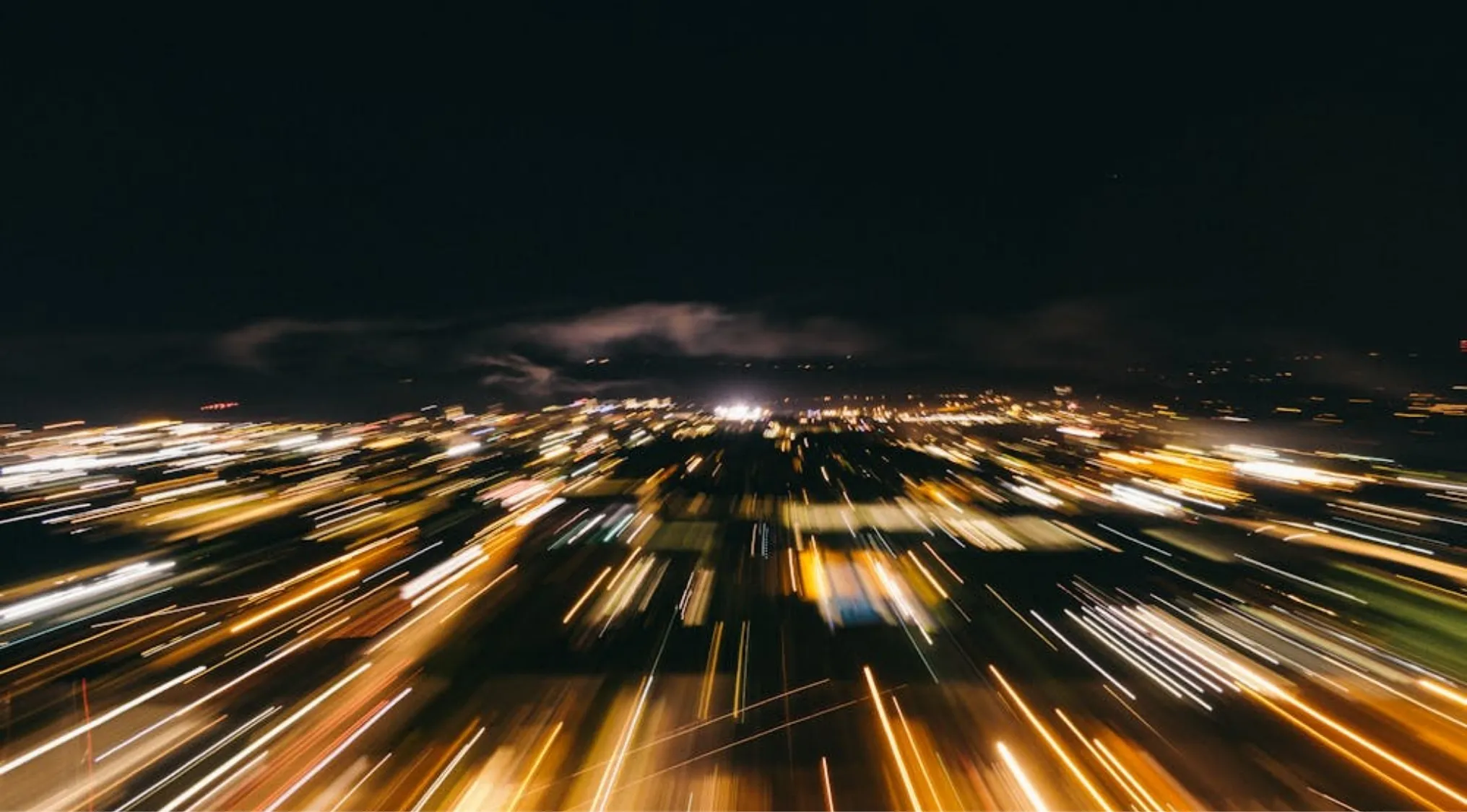 Blurry night city lights streaking across the frame, conveying the immense speed of light.