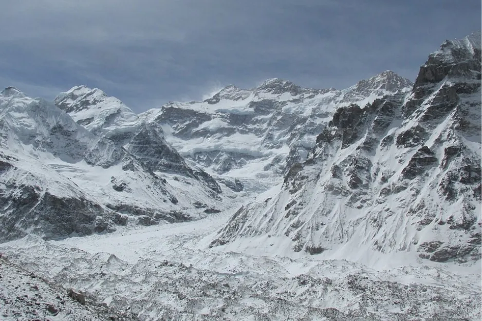 Majestic snow-covered Kangchenjunga, one of the highest mountains, with vast glaciers under a cloudy sky.