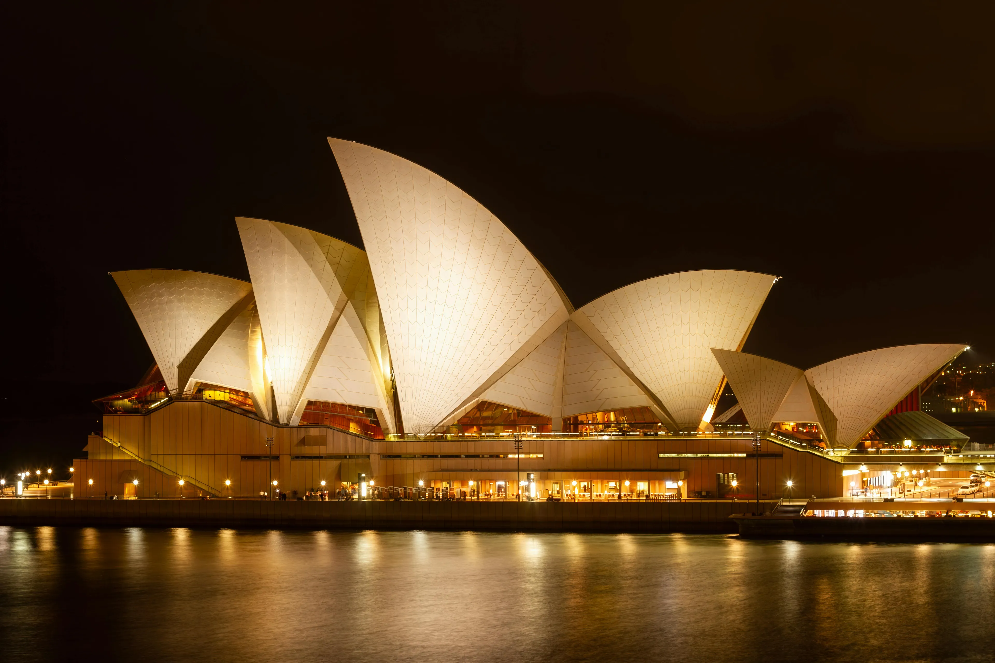 Iconic Sydney Opera House illuminated at night, reflecting on the water. Guess The Country From The Visual Hint of this landmark.