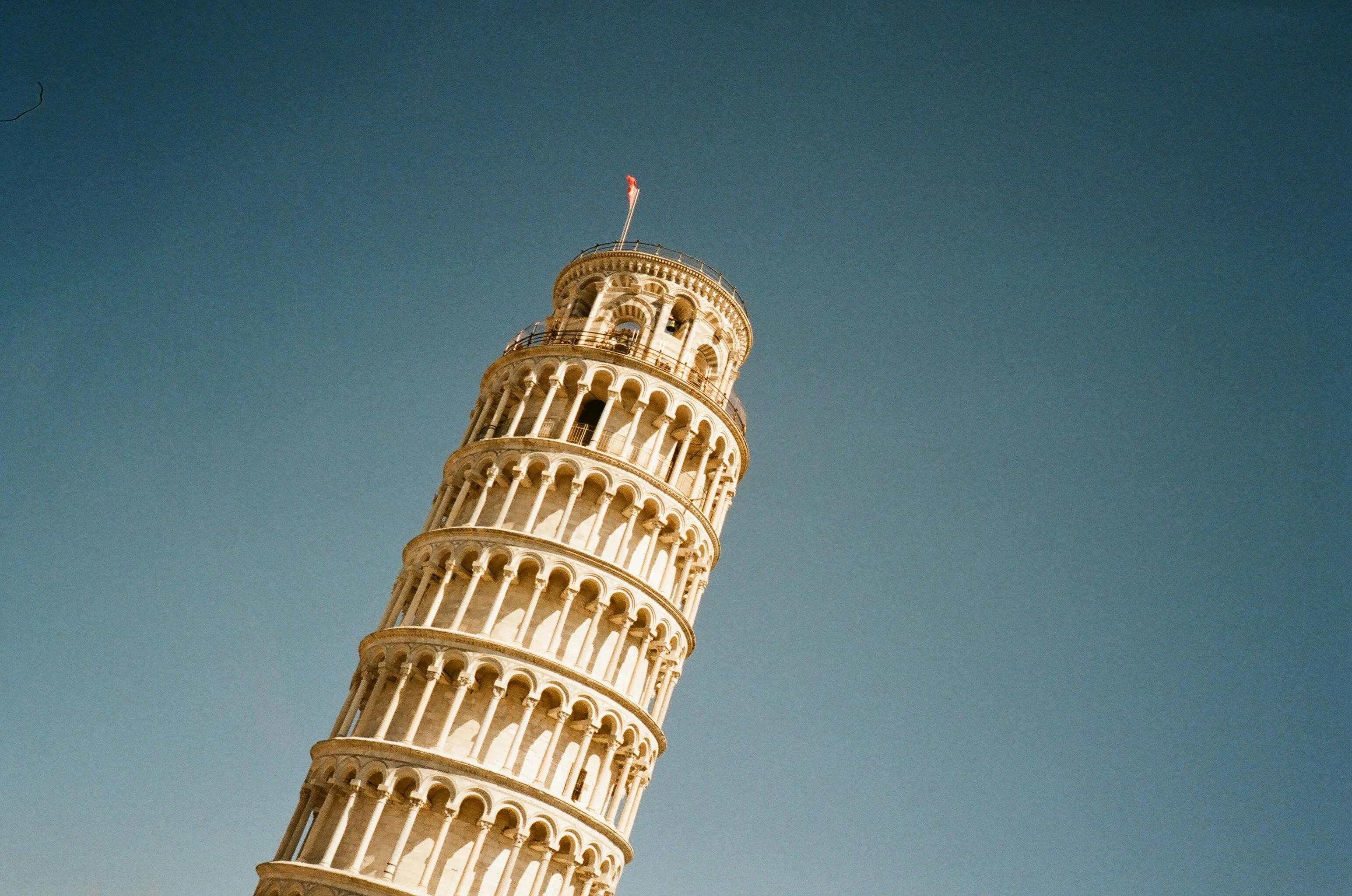Leaning Tower of Pisa tilts towards a clear blue sky. Guess the country from this famous landmark.
