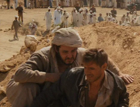 Two men in dusty clothing crouch outdoors with a crowd behind them, evoking a classic movie line mood today.