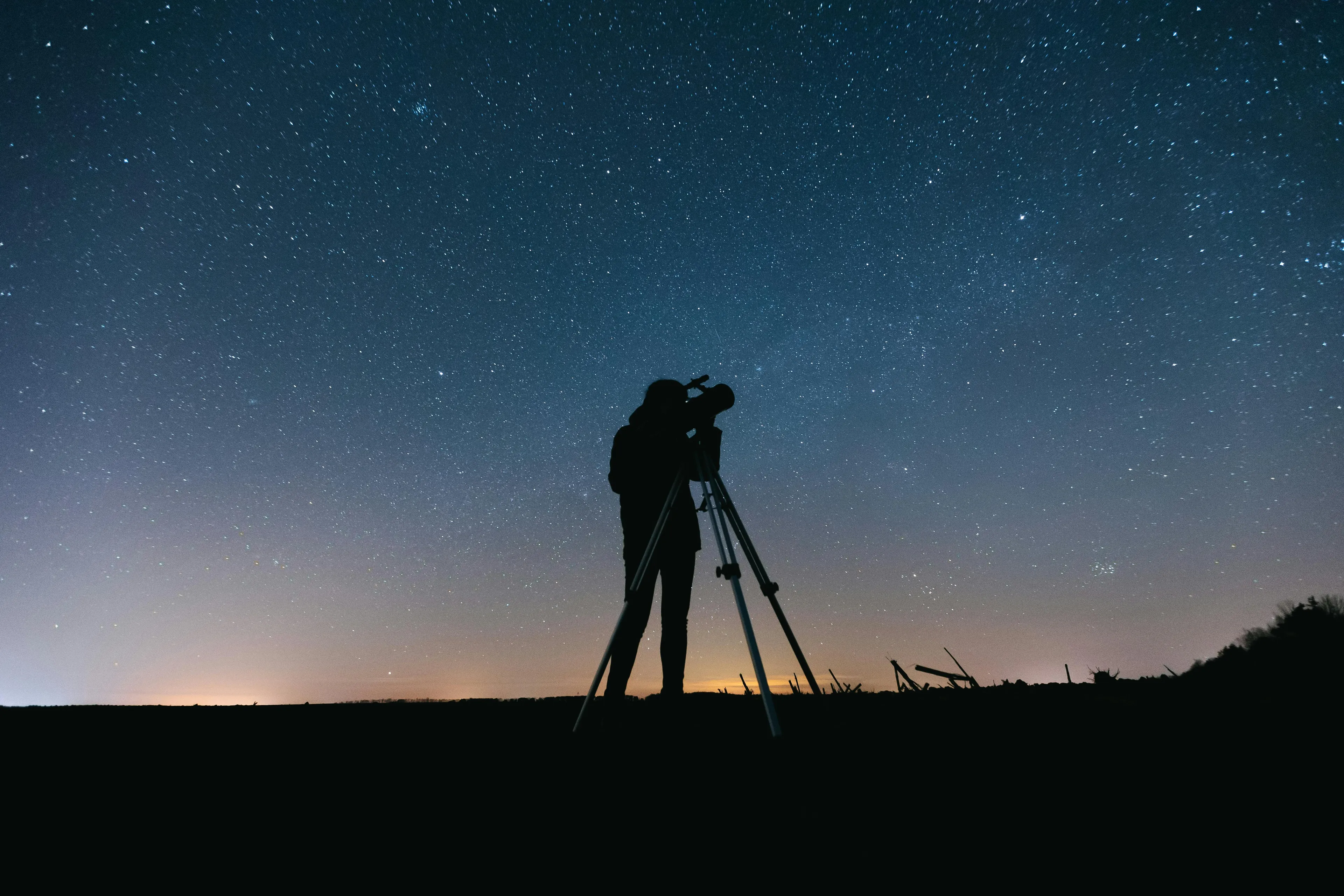 Person using a telescope to observe the night sky filled with stars, engaging in astronomy as a hobby.