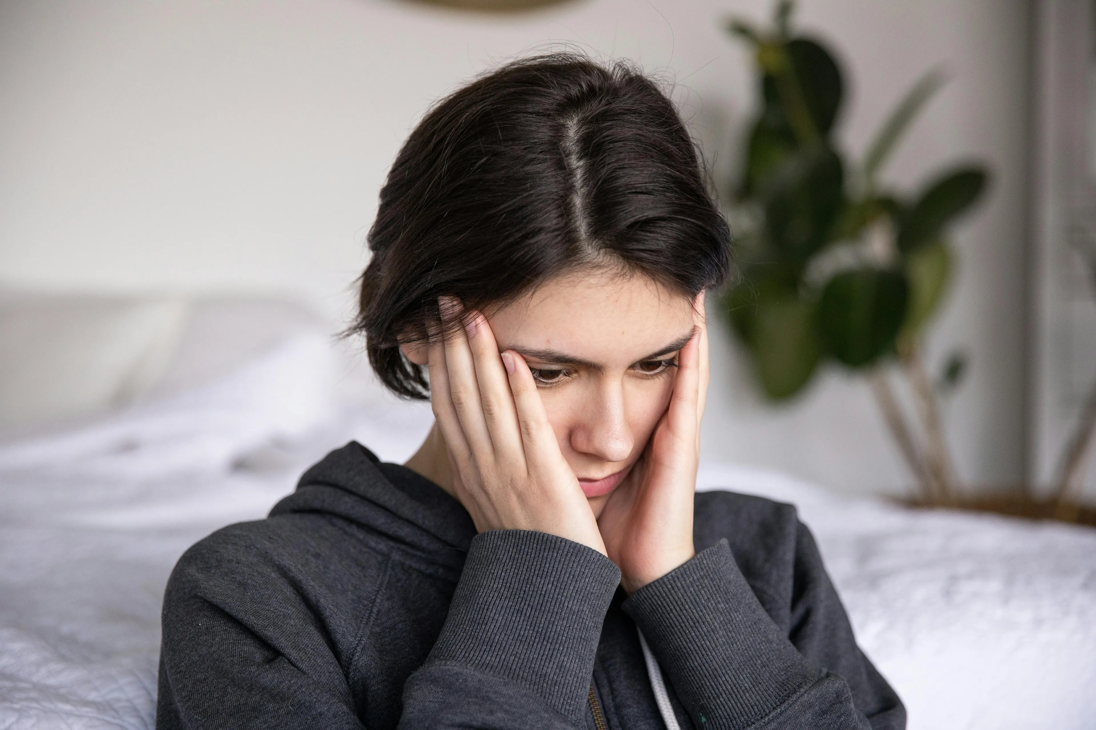 Young woman thinking deeply at home, illustrating the concept of left-brain or right-brain decision-making style.