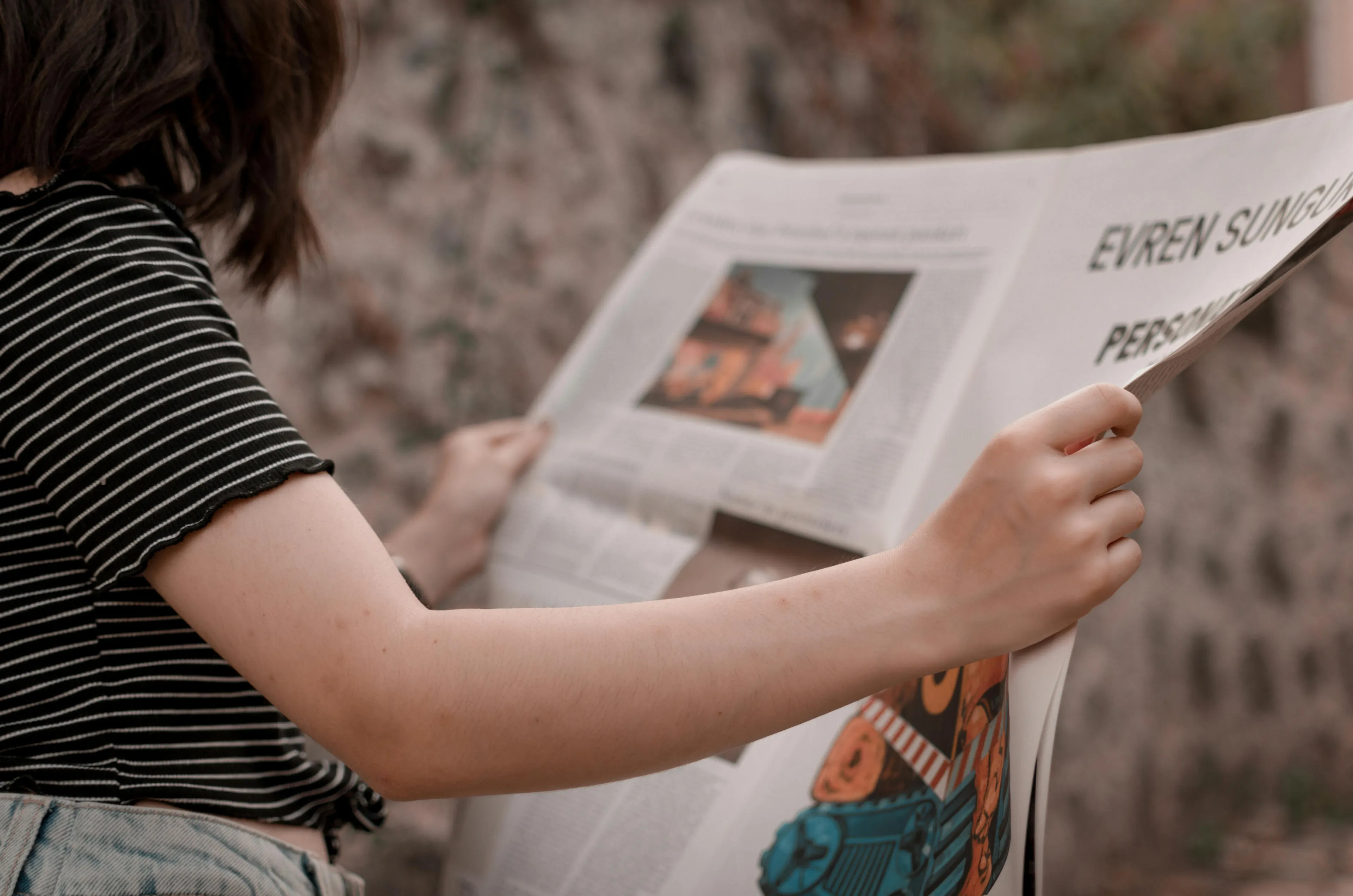 Person reading a newspaper outdoors, illustrating left-brain or right-brain thinking while engaging with the news.