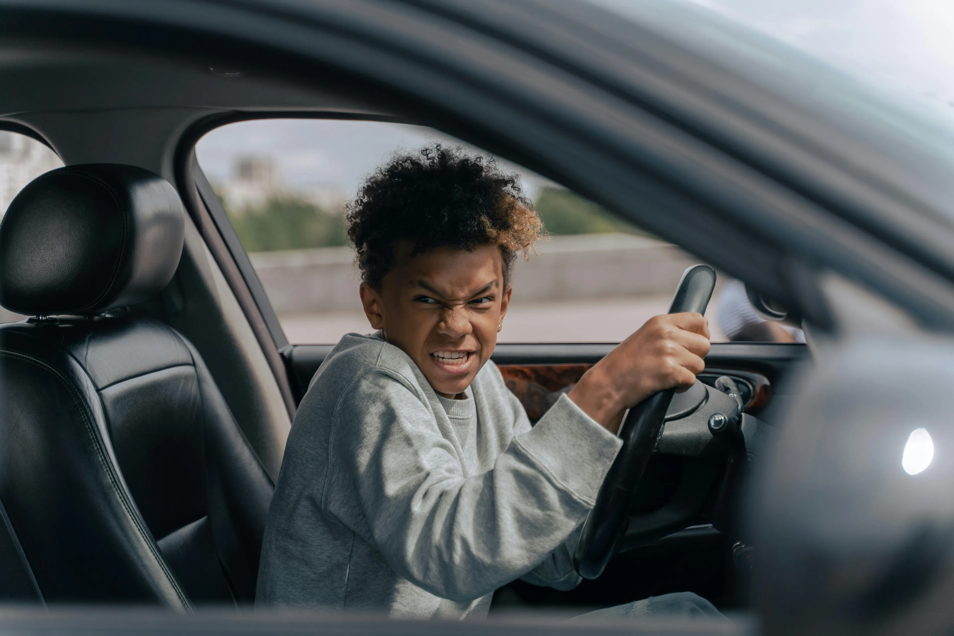 Young person showing upset expression inside a car steering wheel, exploring left-brain or right-brain instincts.