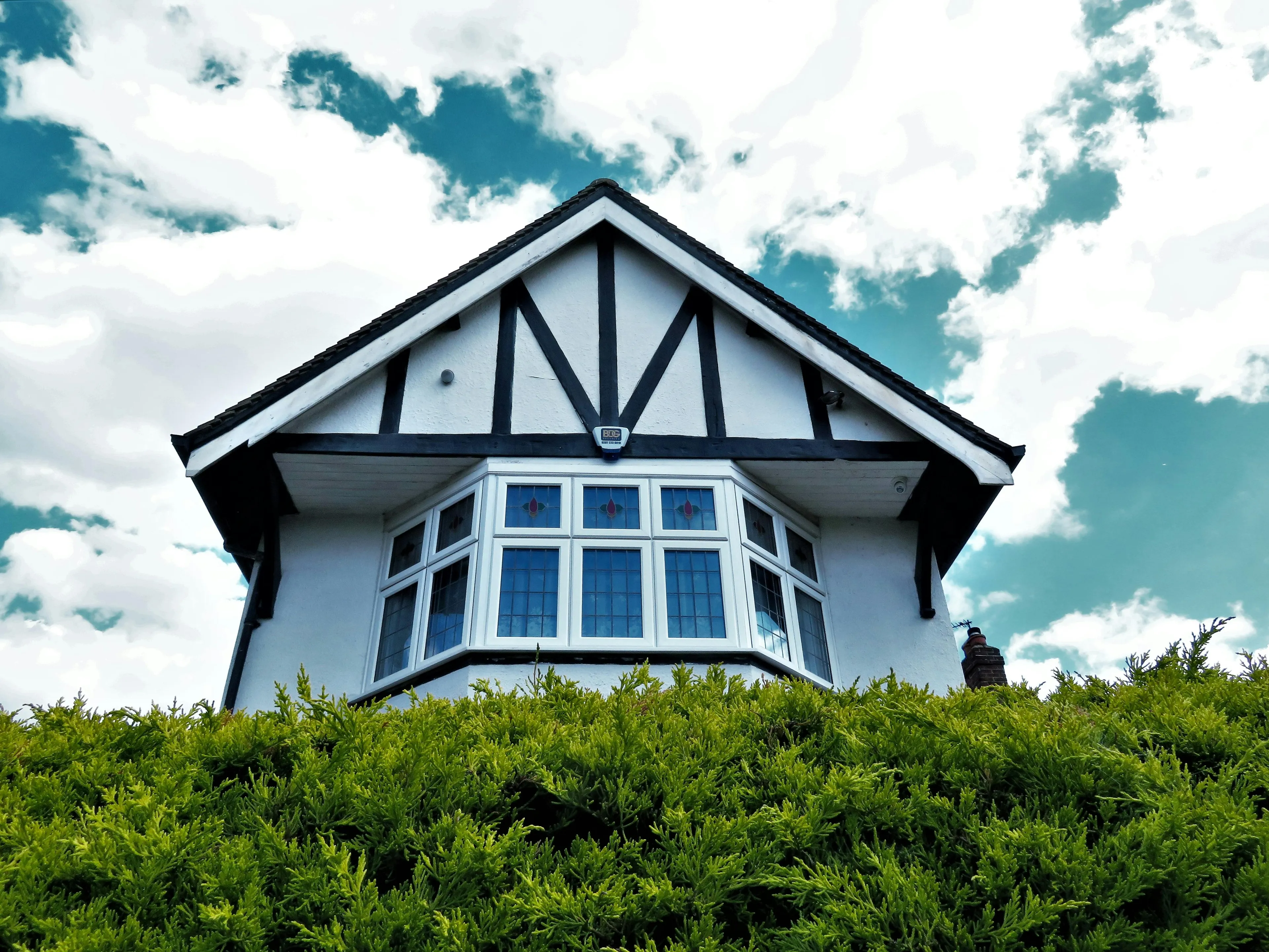 House exterior with bay windows and Tudor-style design under a partly cloudy sky, representing dream house features.