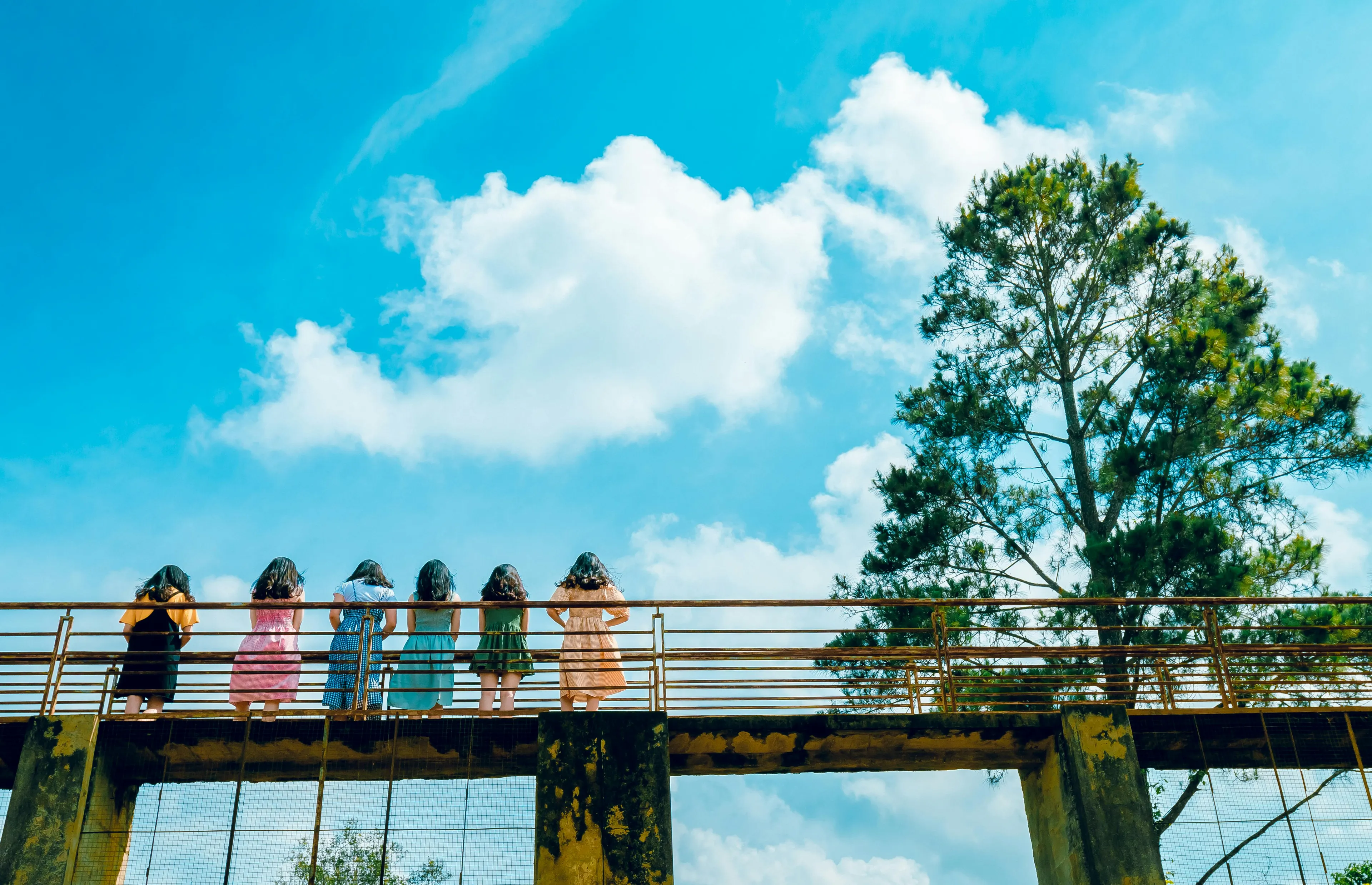 Group of people standing on a bridge under blue sky representing left-brain or right-brain and feeling most alive at different times