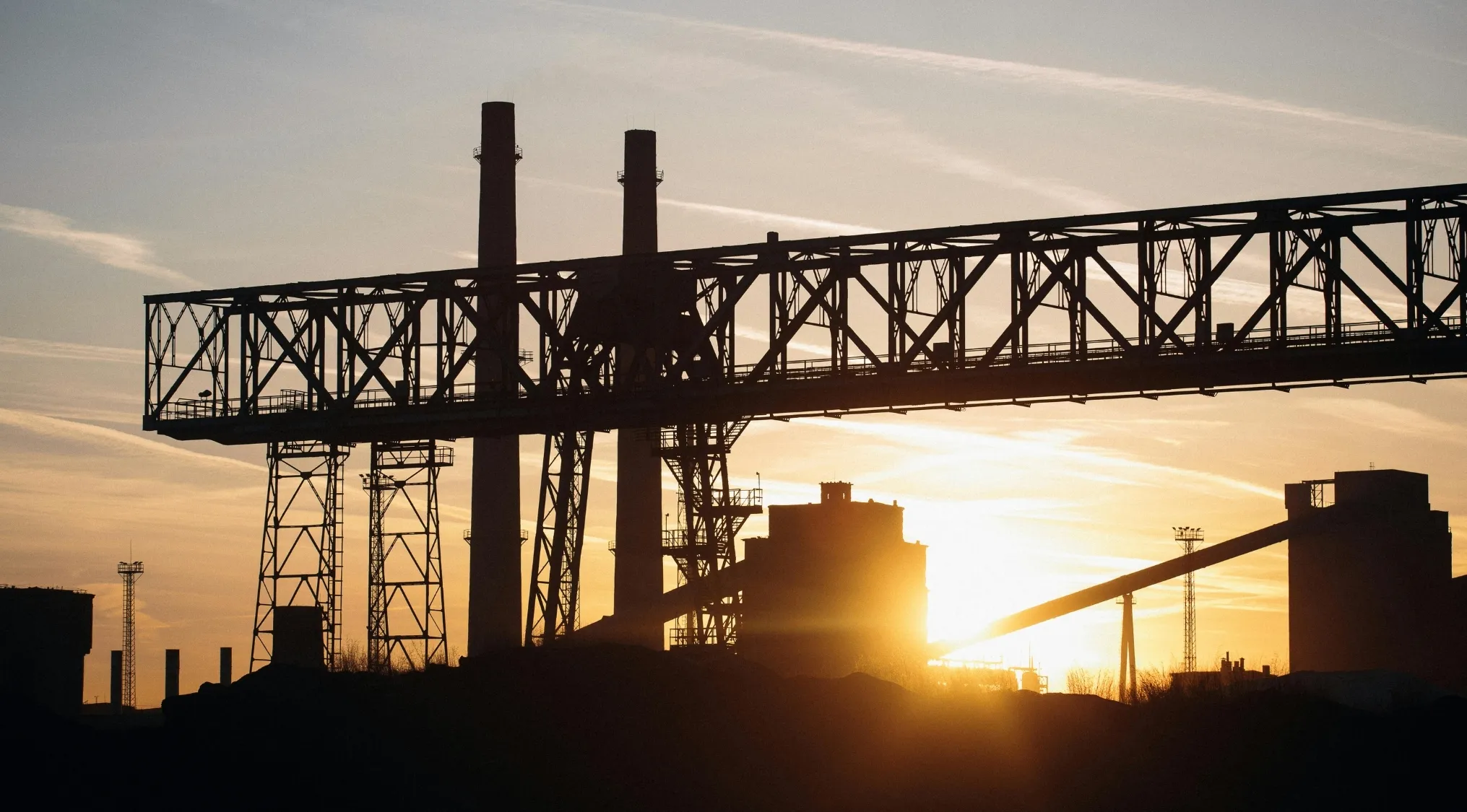 Industrial Revolution factory silhouette at sunset showing steel structure and chimneys driving 18th century growth
