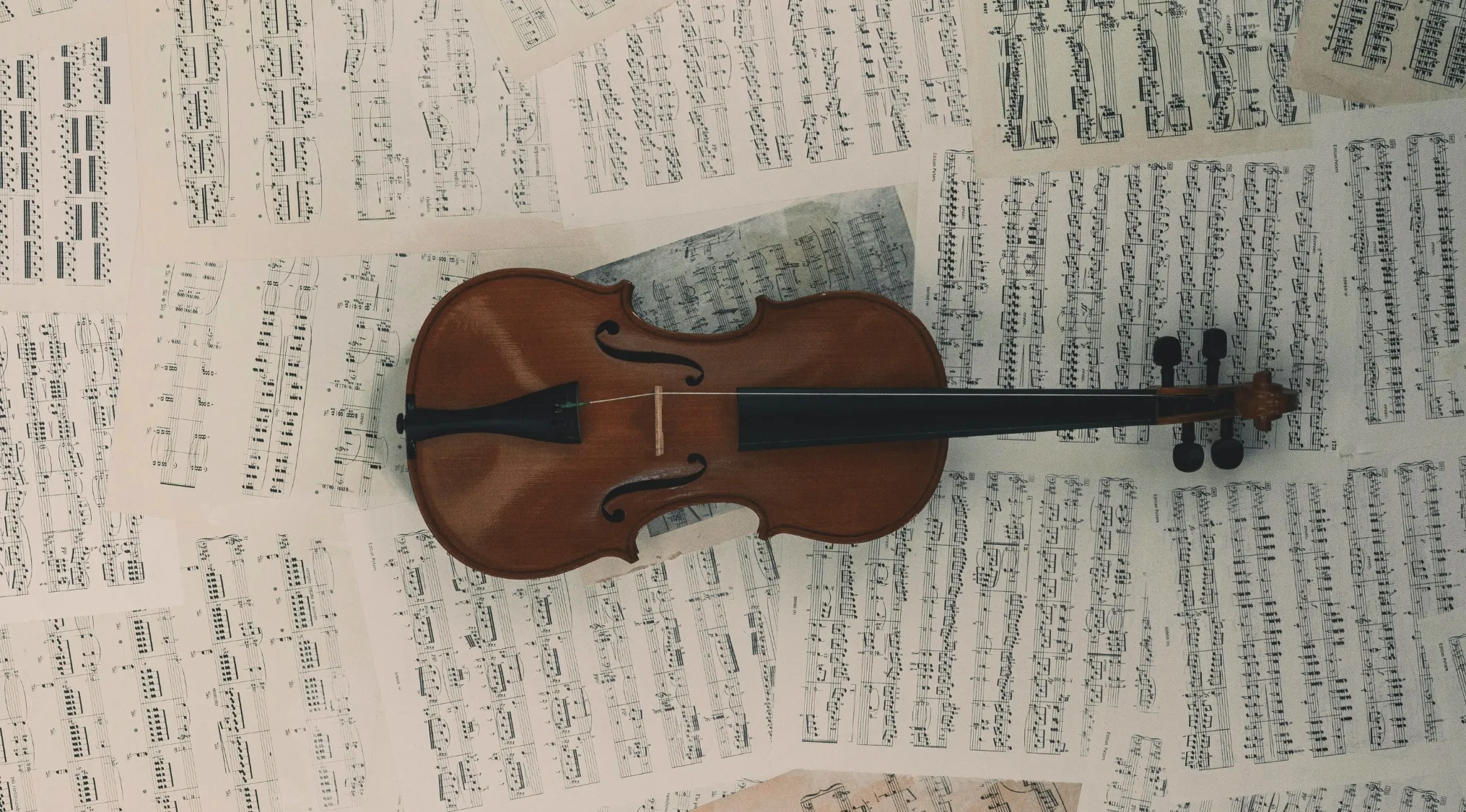 Violin resting on scattered music sheets with notes illustrating music notation and crescendo concepts.