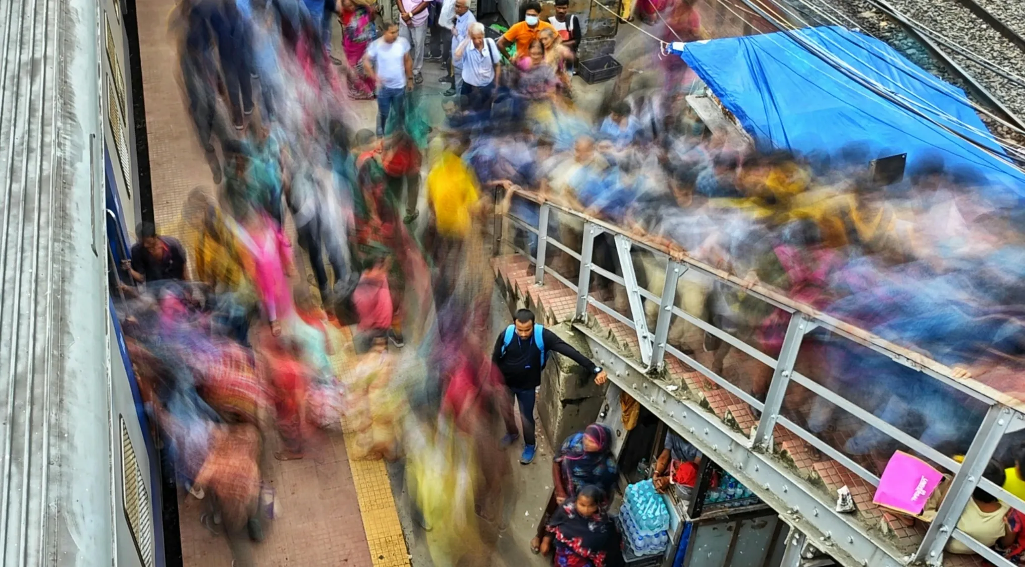 Crowded train platform with many people in motion, illustrating high population density in a busy urban area.