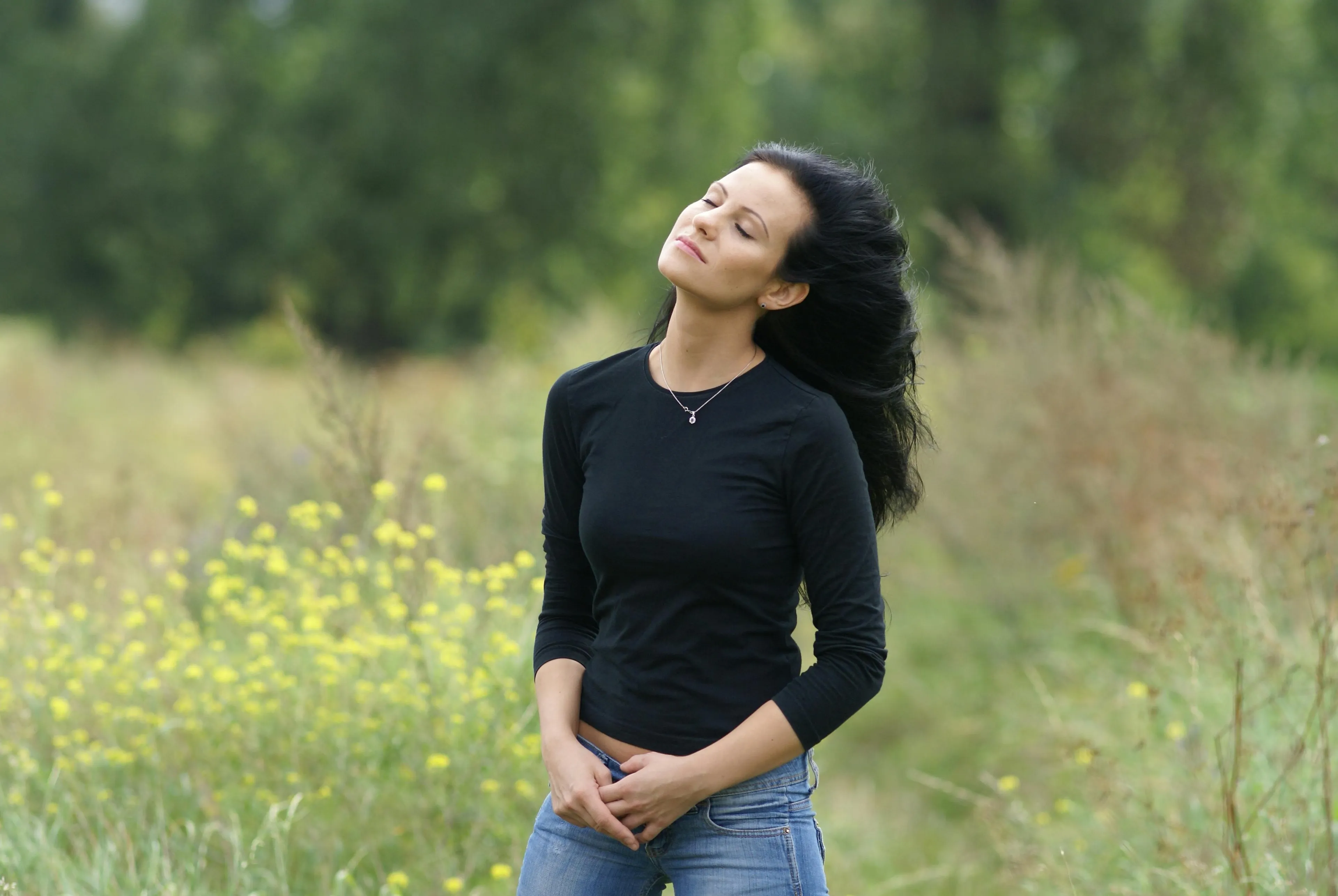 Young woman outdoors breathing deeply in nature, illustrating high school biology human body quiz concept.