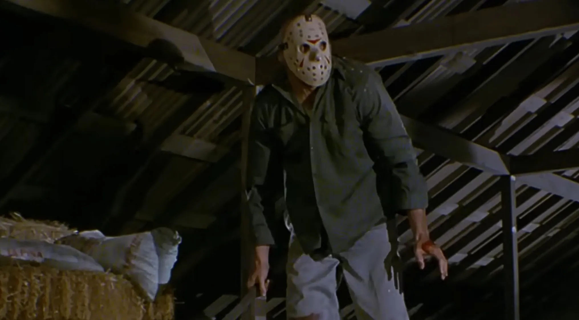 Horror movie trivia: An antagonist wearing a hockey mask and holding a machete, standing in a dimly lit attic.