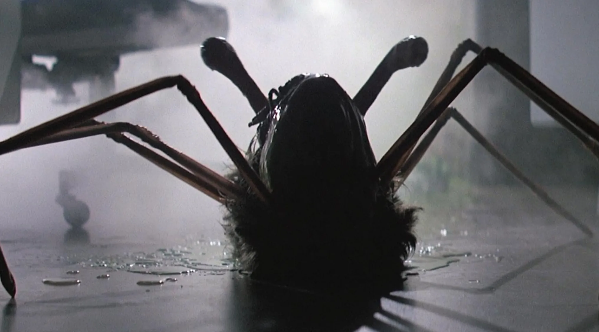 Horror movie trivia: A shape-shifting alien, dark and spider-like, with long legs, lies on a wet, misty floor.