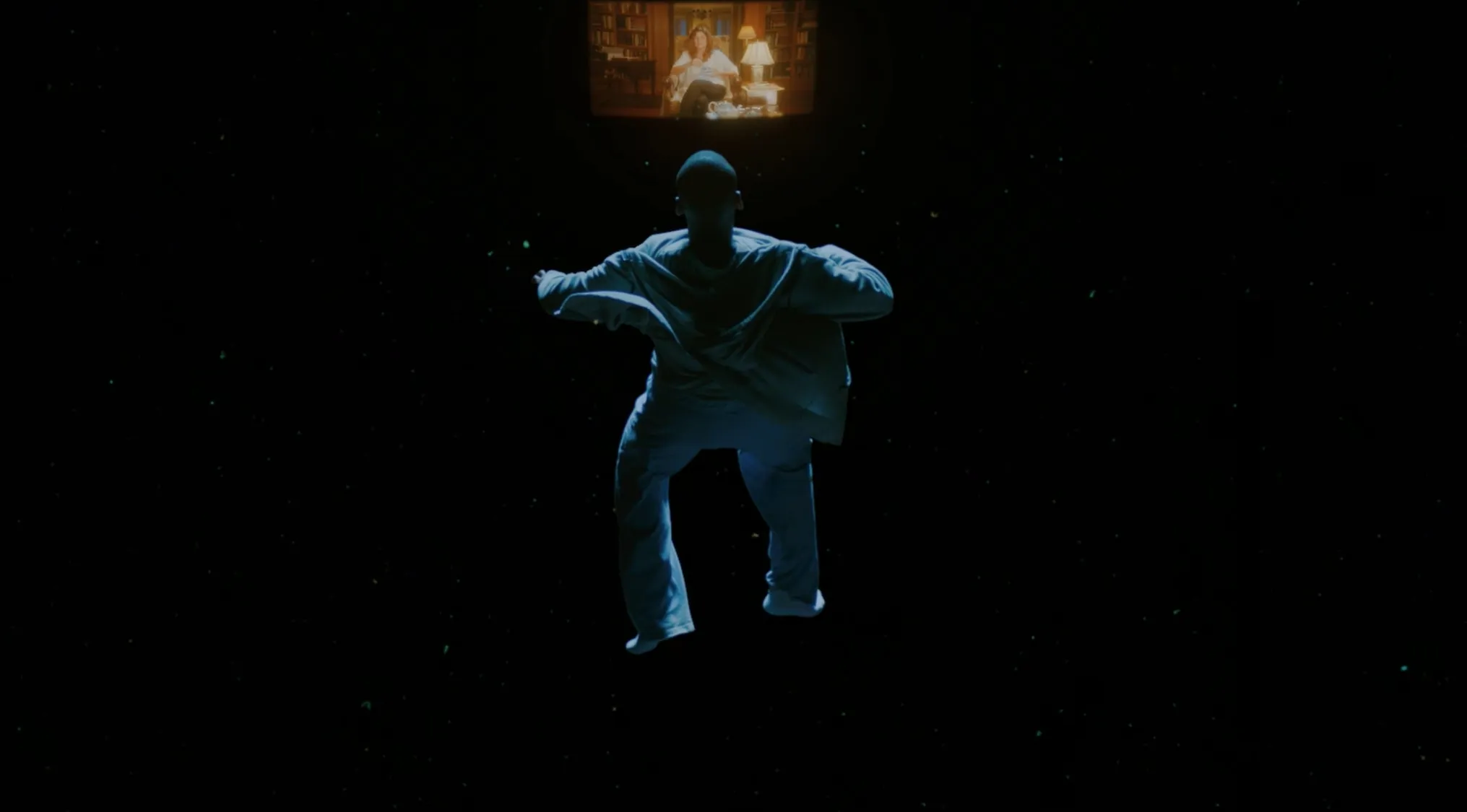 A man in light clothes floats in darkness, looking up at a projection of a woman in a room; horror movie trivia scene.
