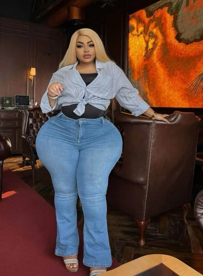 A woman posing in a room with highly exaggerated, edited hip proportions, demonstrating Instagram Reality.