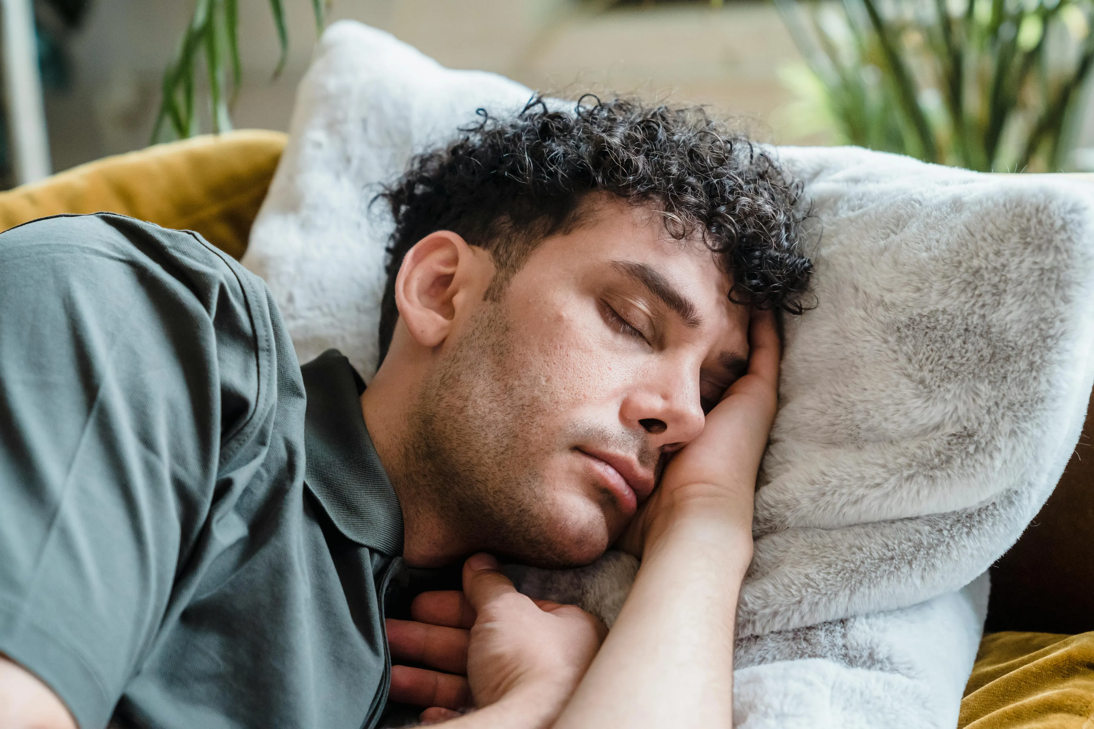 A man with curly hair taking a long nap on a soft pillow. A perfect rainy-day activity for relaxation.