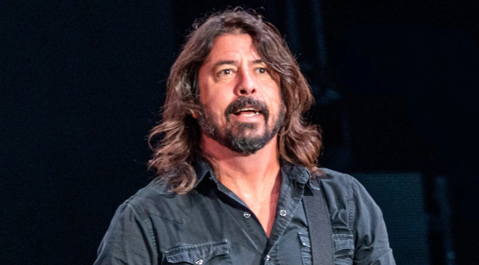 Dave Grohl, frontman for a rock band, with long hair and a beard, wearing a black shirt. Trivia night question.