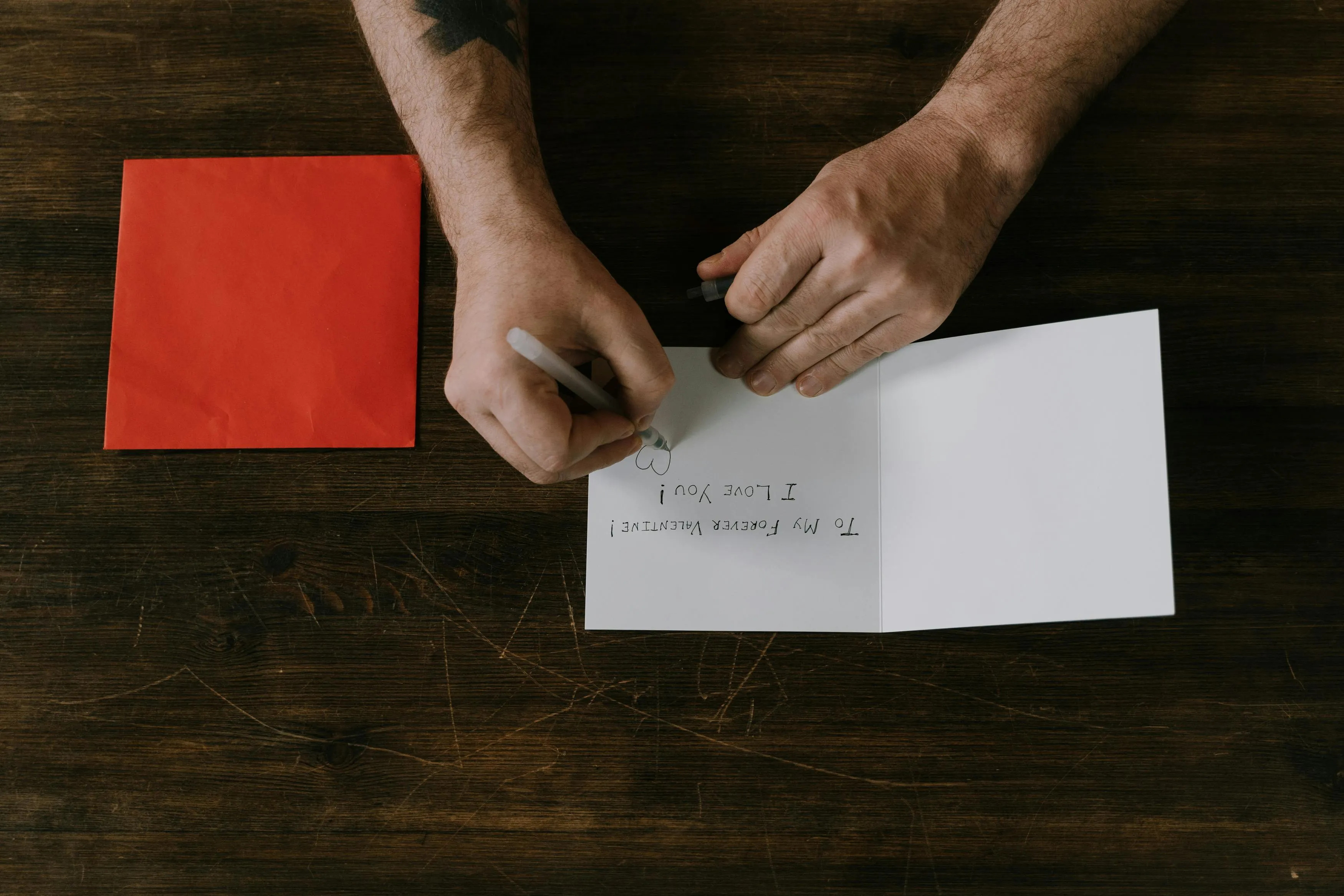 Hands writing a handwritten card, expressing love with a heart drawing, a thoughtful housewarming gift.