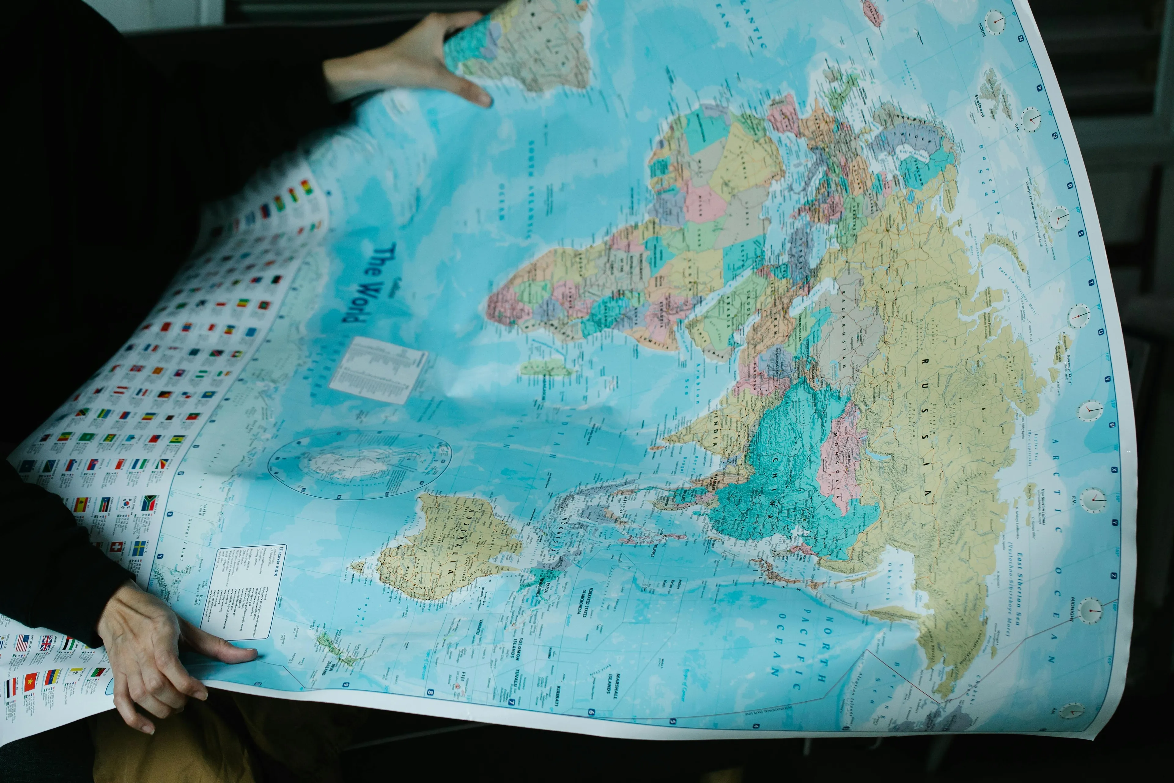 A person holding a world map. Perfect for trivia night questions about geography and the Equator.