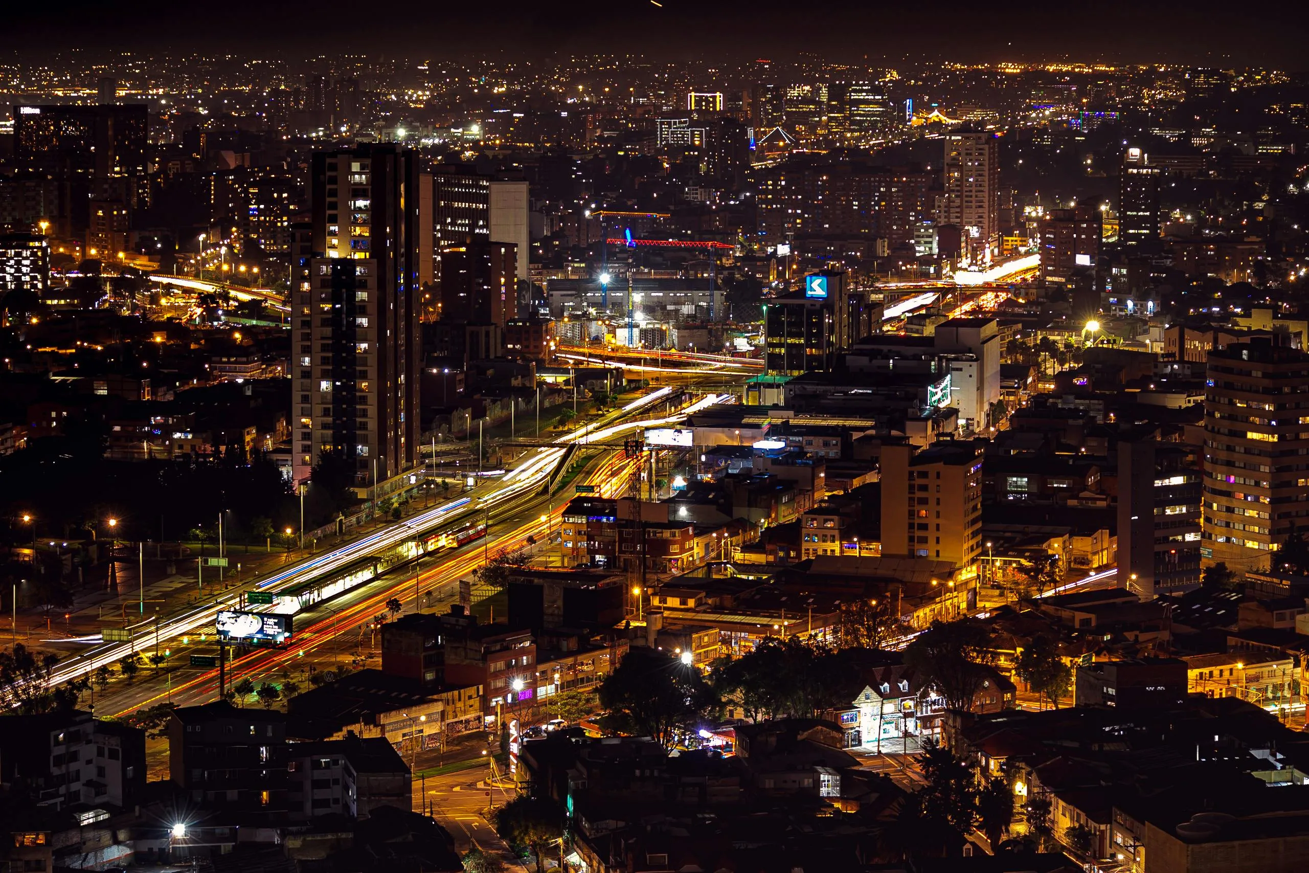 A vibrant night aerial view of Bogotá, Colombia, with streaks of light from traffic on busy roads. Win trivia night!