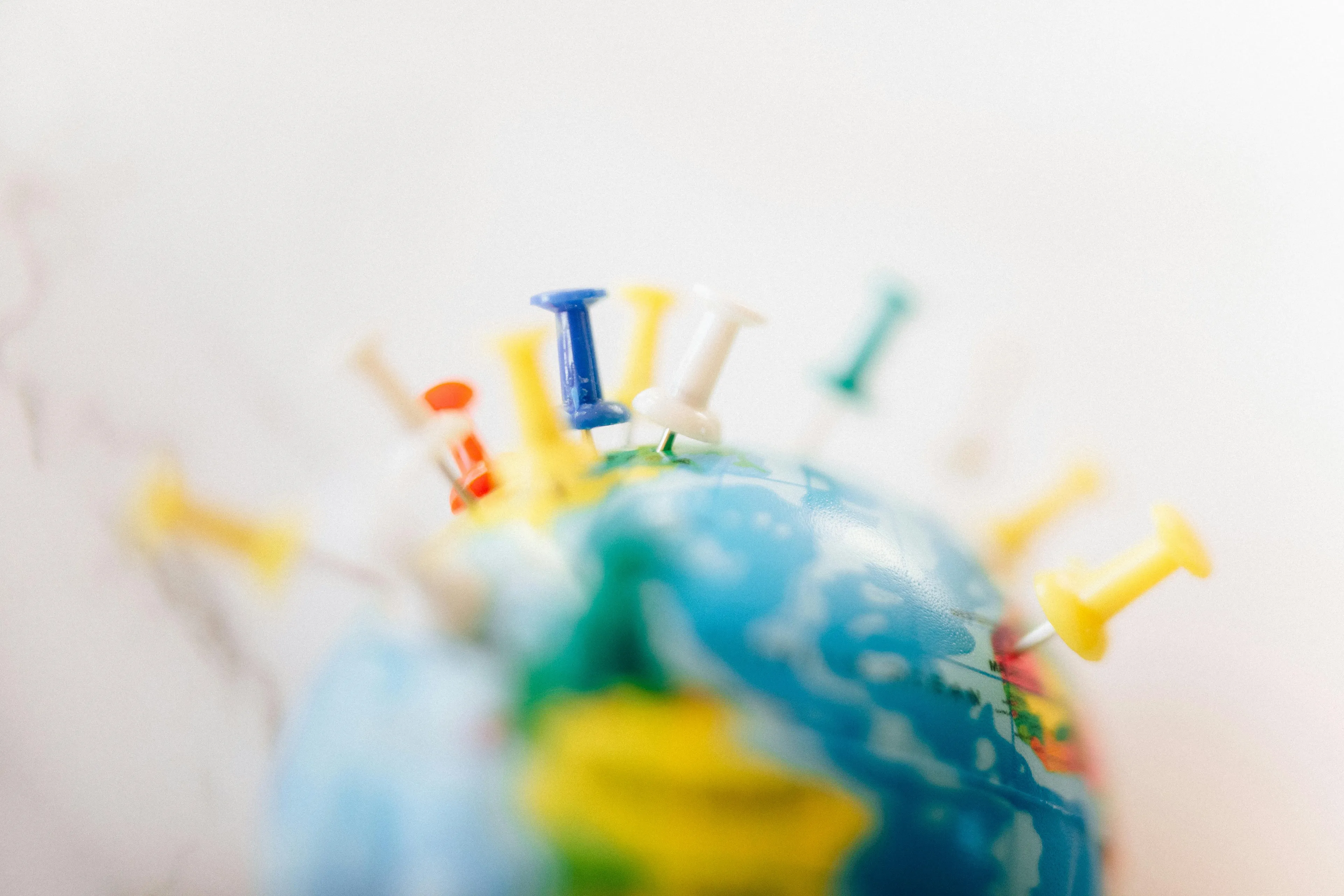 Close-up of a globe covered in colorful pushpins, signifying travel choices. This image explores reactions to rejection.