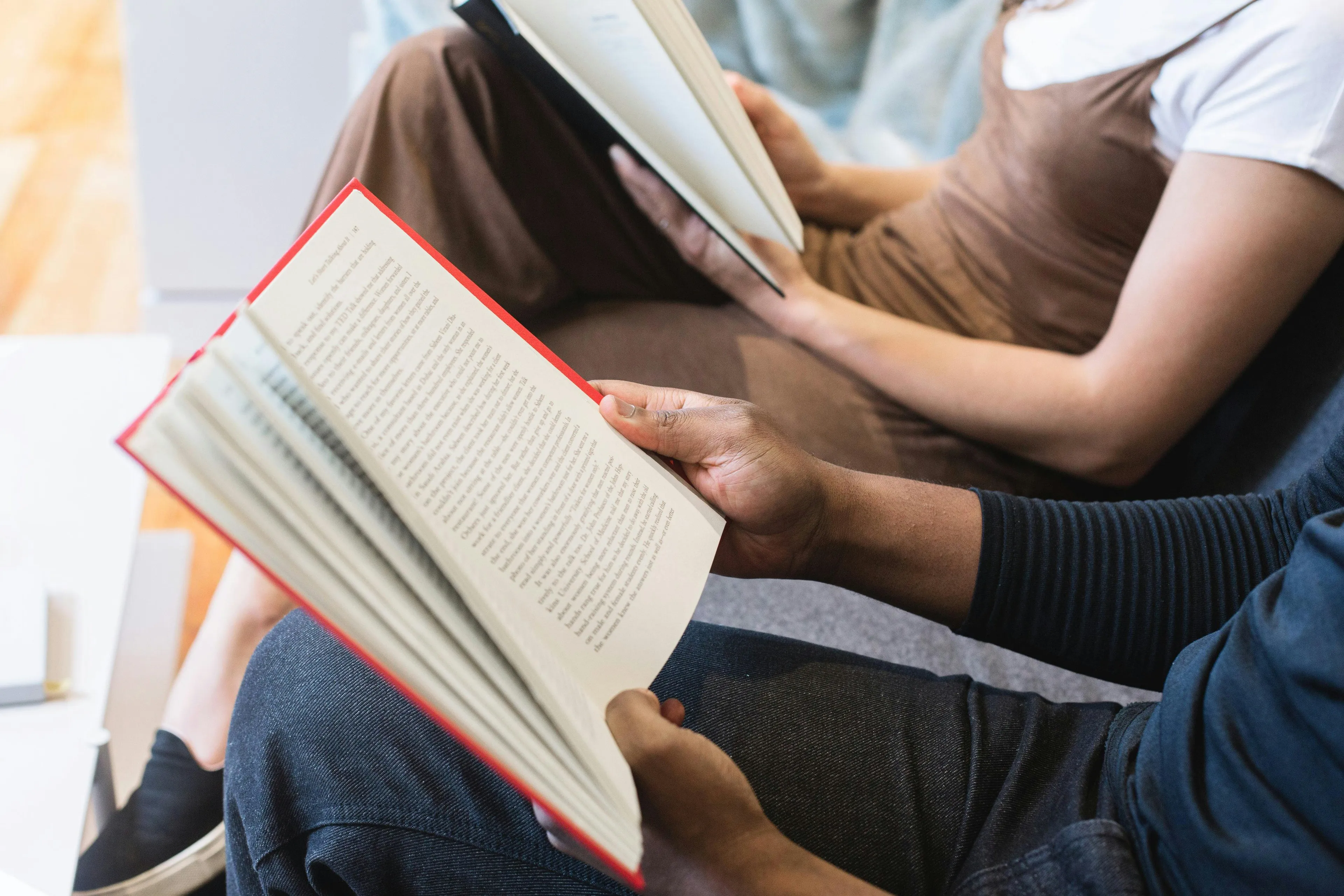 Two people seated, one in dark jeans, the other in a brown dress, reading books. Exploring reaction to rejection.
