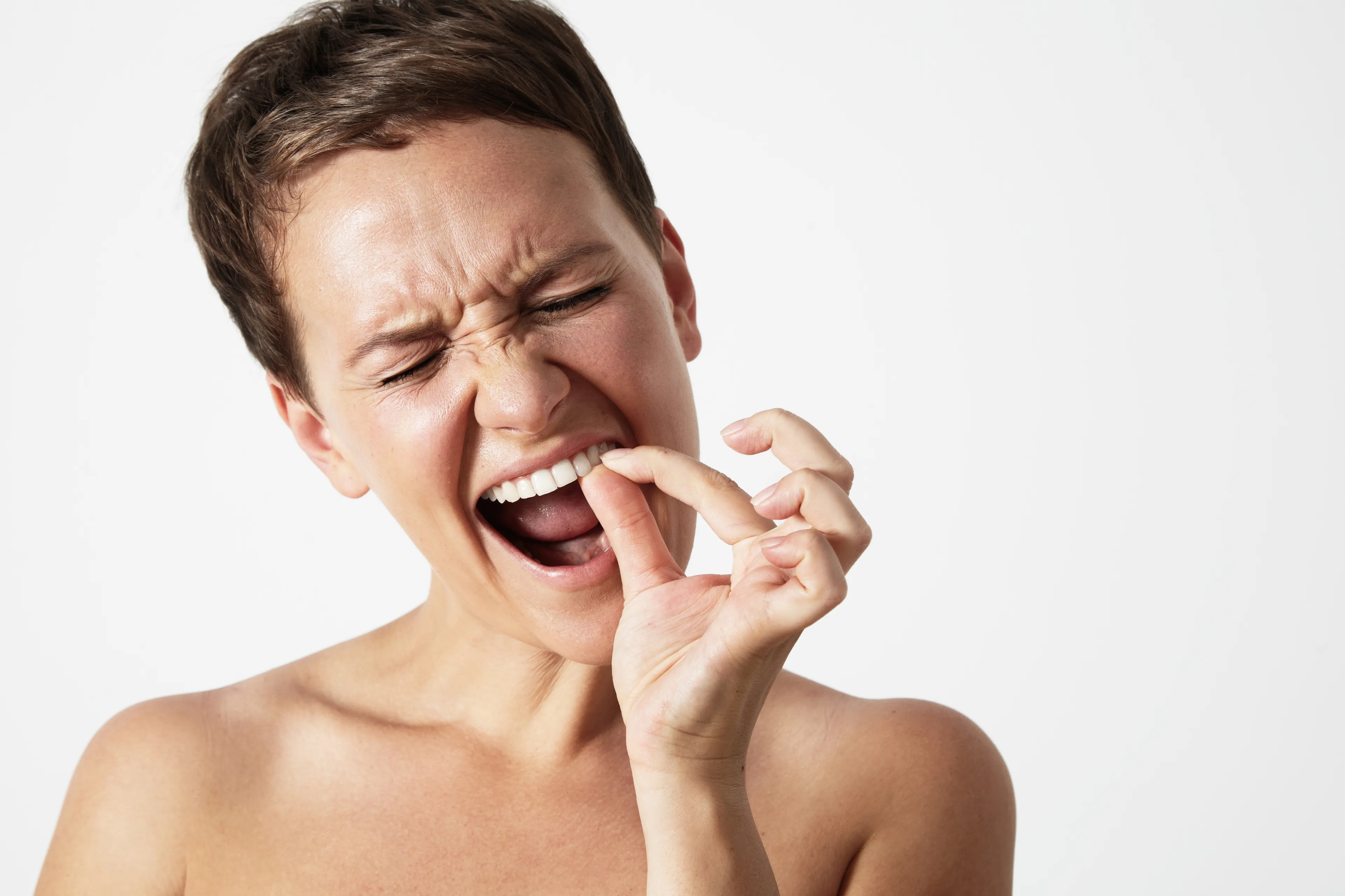 A woman grimacing, picking at her teeth, embarrassed about the spinach. How do you apologize effectively?