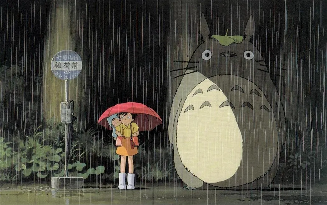 Satsuki, Mei, and My Neighbor Totoro stand in the rain at a bus stop, a comfort movie scene.