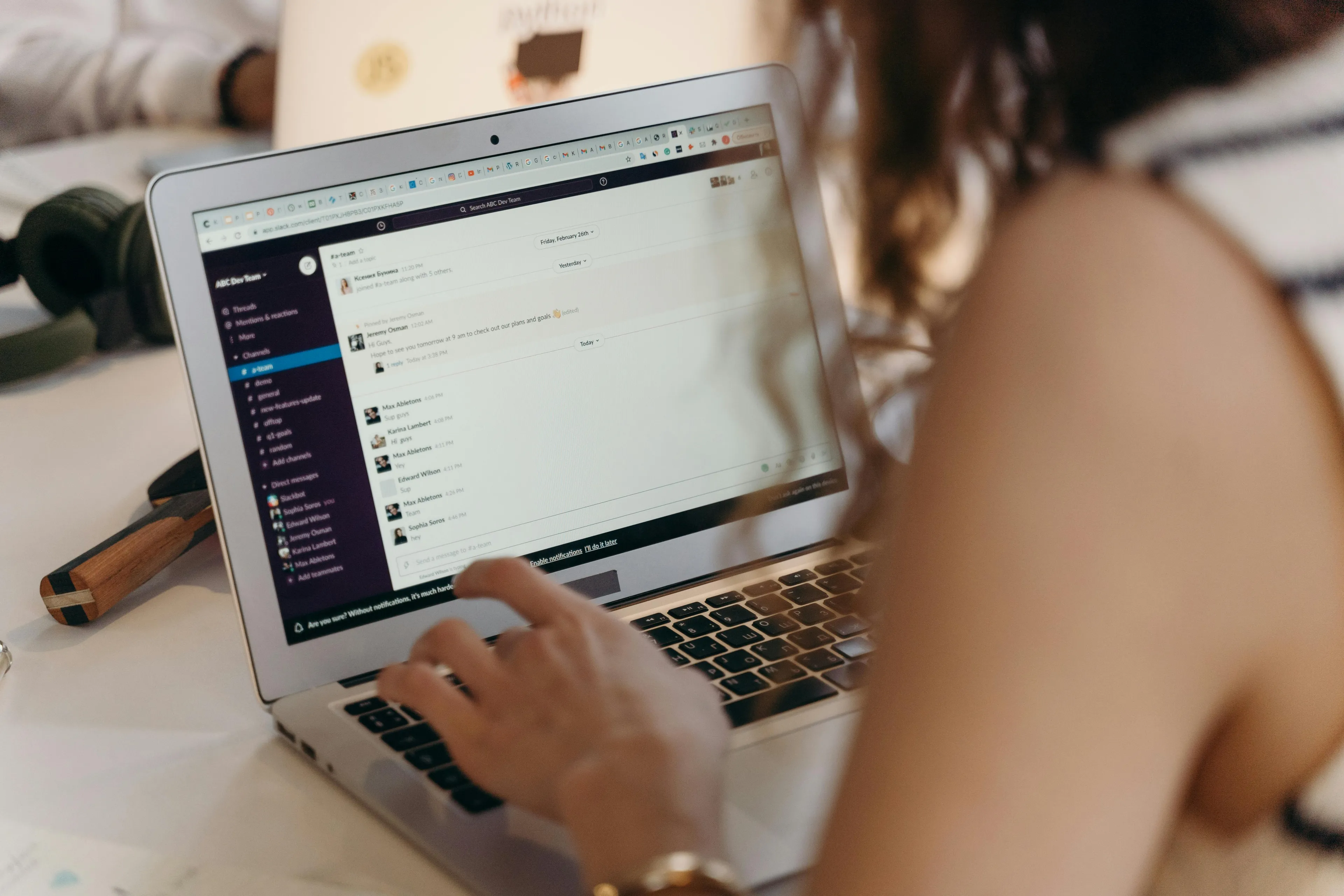 Person types on a laptop, viewing a Slack interface. A coworker emails about a typo. How do you apologize effectively?