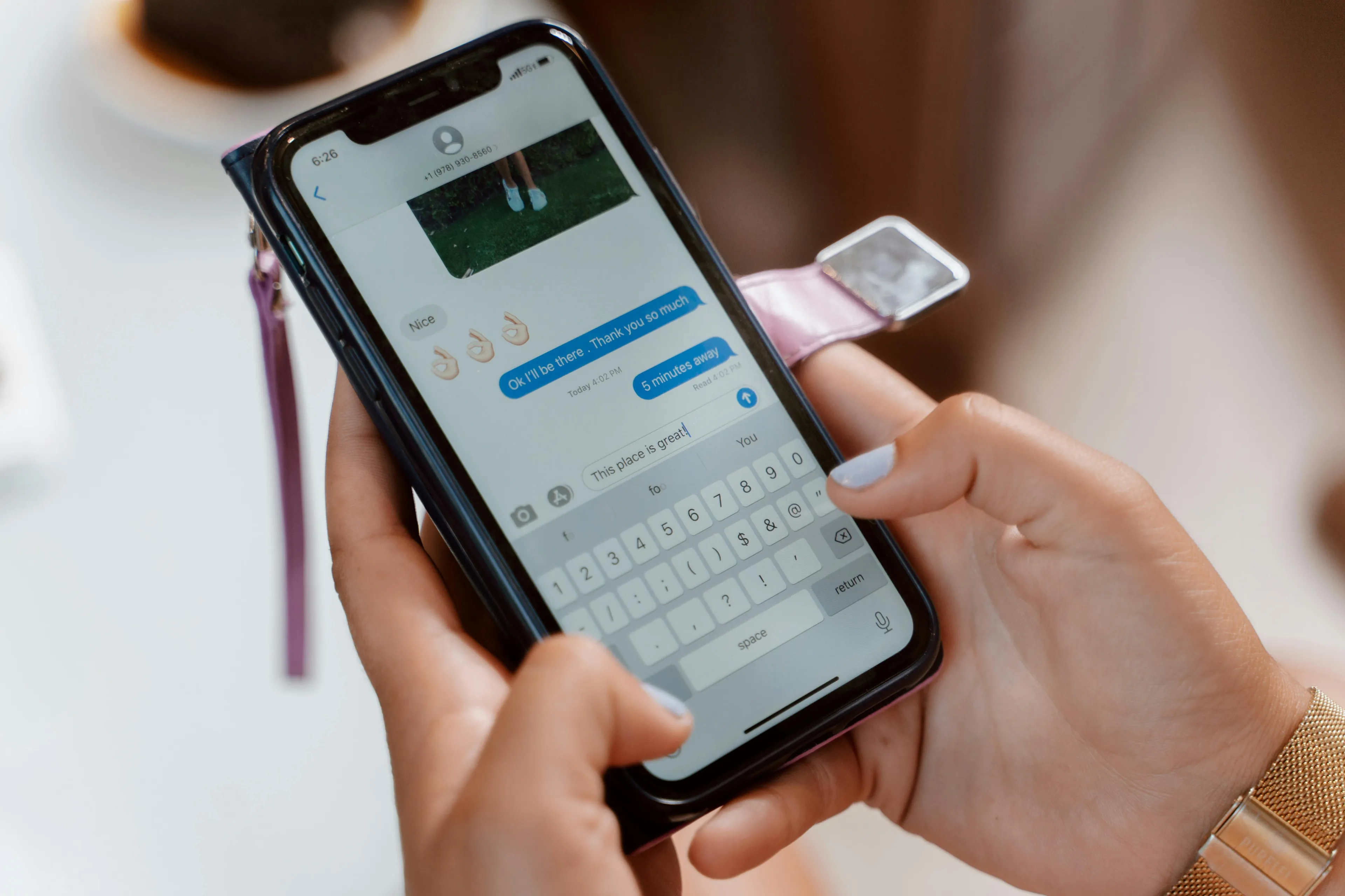 Hands texting on an iPhone with emojis and a photo in the chat, illustrating how to apologize for accidental messages.