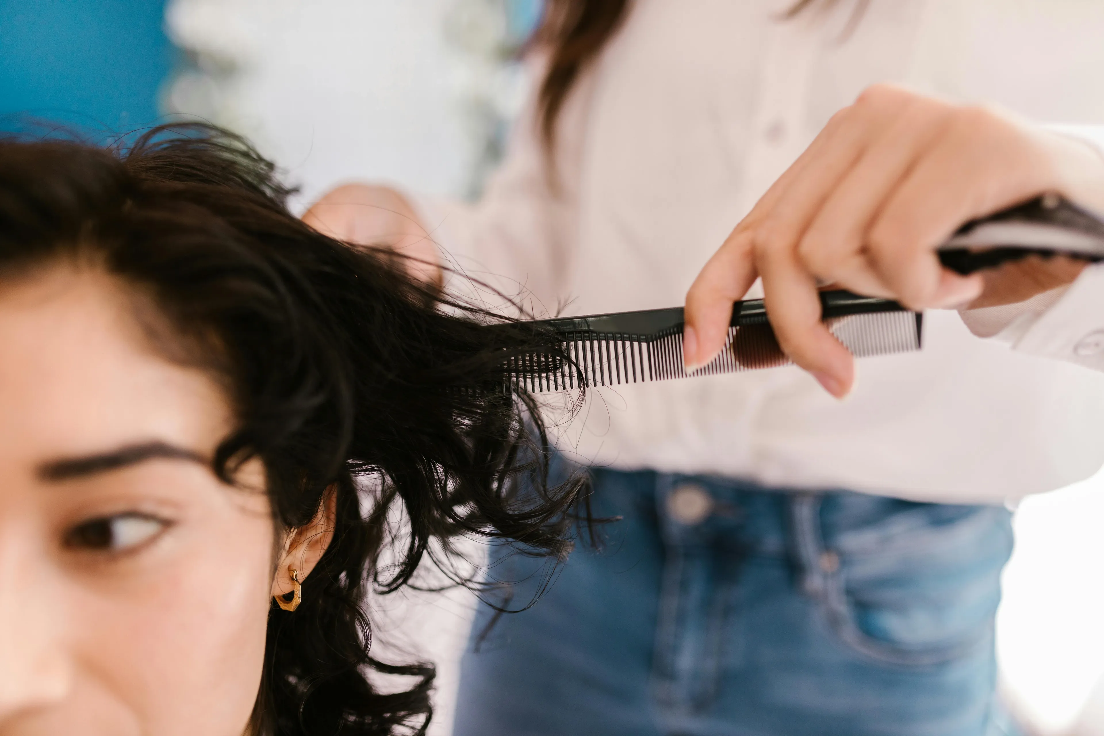 A person with dark hair looks away as another combs their hair, representing the Reaction To Rejection quiz.
