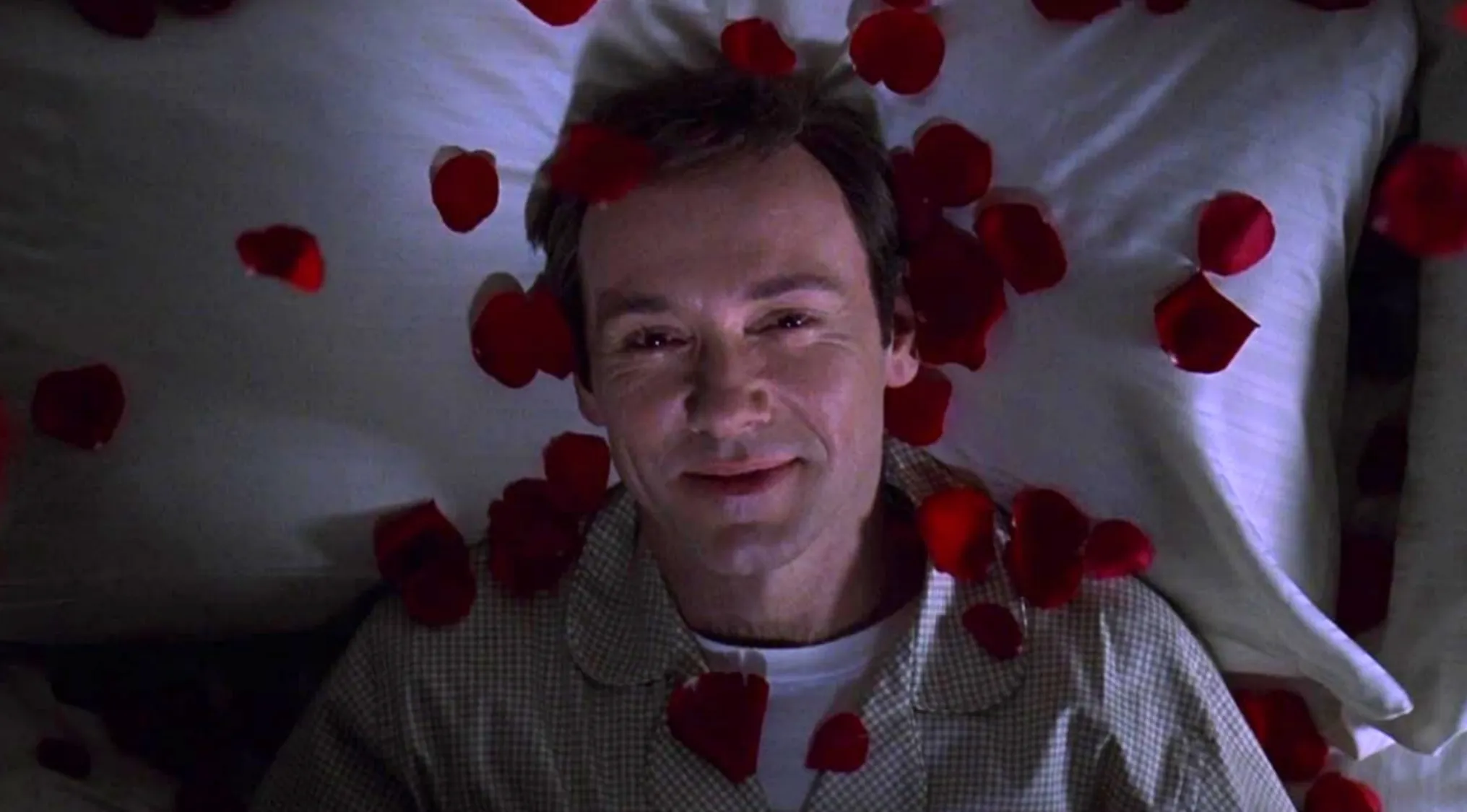 Kevin Spacey as a family man, smiling amidst red rose petals on a pillow. The Ultimate Movie Quiz.