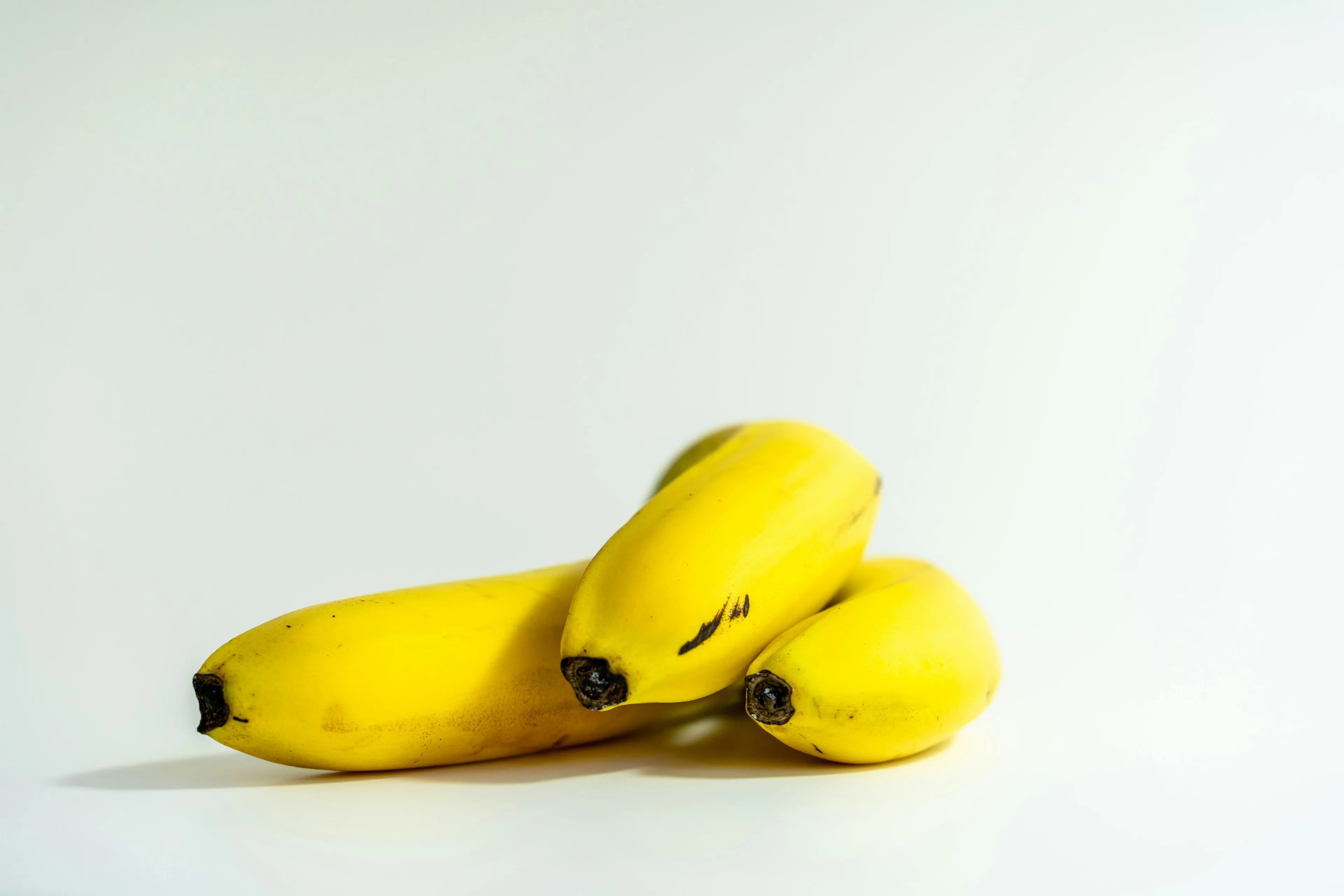 Three ripe yellow bananas, a favorite comfort snack, against a bright white background.