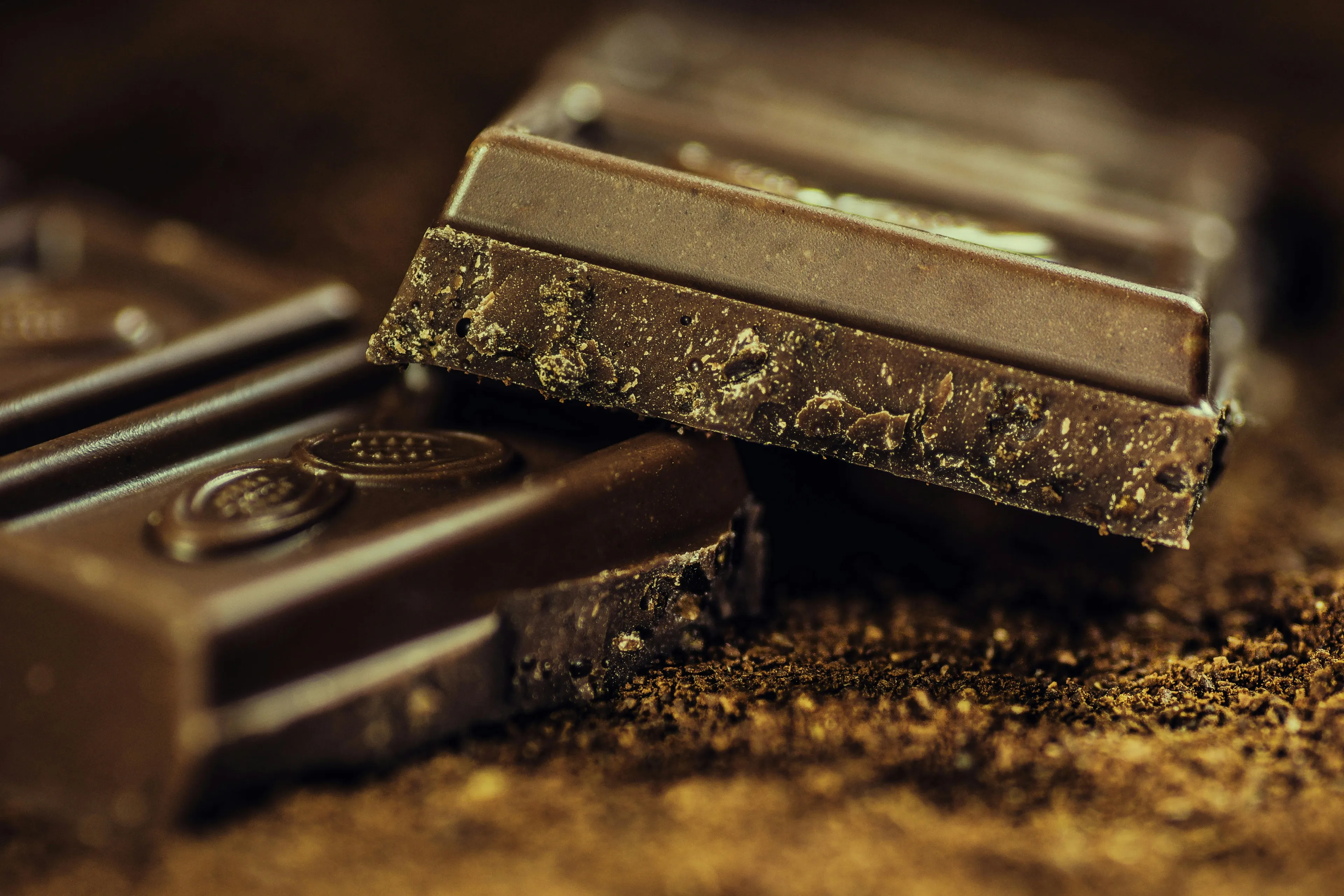 Macro shot of stacked dark chocolate bars with crumbs, highlighting its rich texture and decadent appeal as a comfort snack.