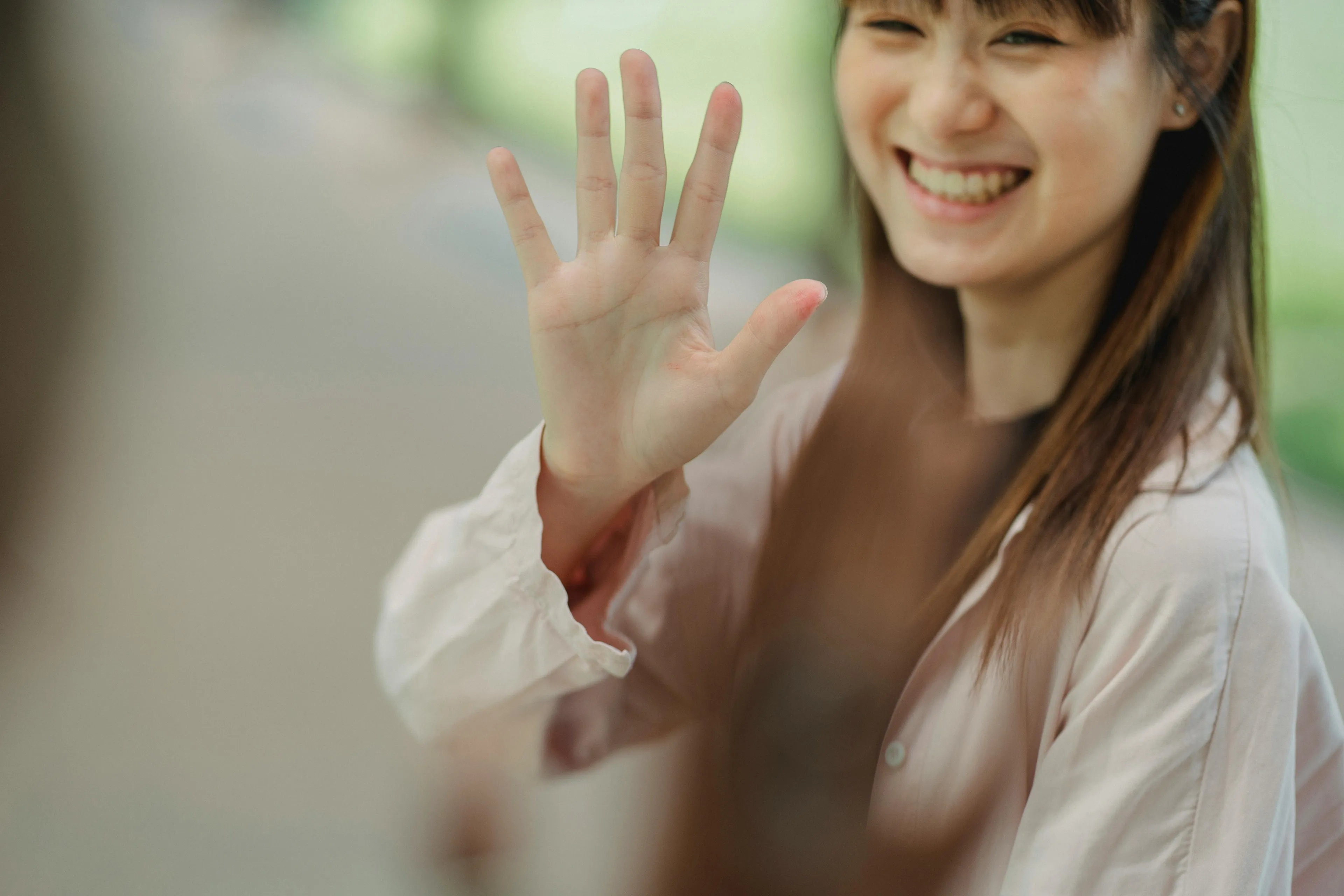 Smiling woman holds up her hand, appearing to say stop. This image relates to a Reaction To Rejection Quiz.