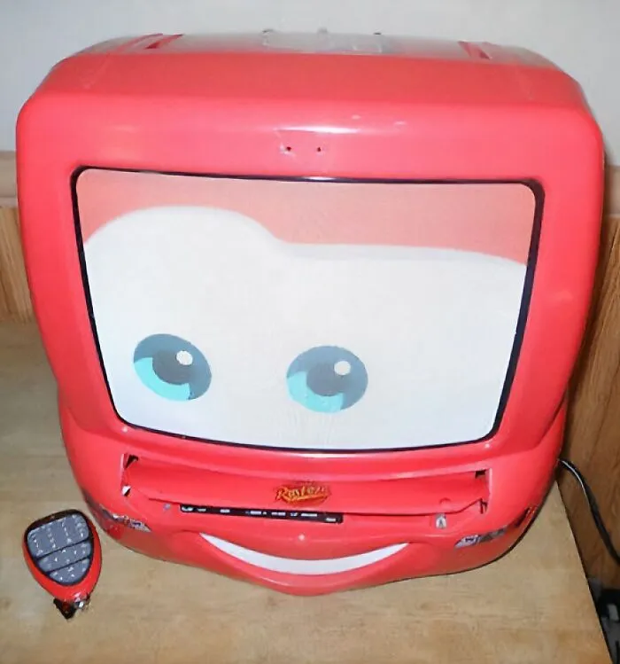 A red Lightning McQueen shaped TV and VCR combo with a remote, designed for kids. It makes people take a trip down memory lane.