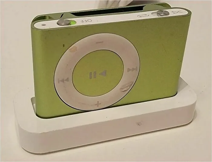 A nostalgic green iPod Nano in a white charging dock, stirring a trip down memory lane for many.