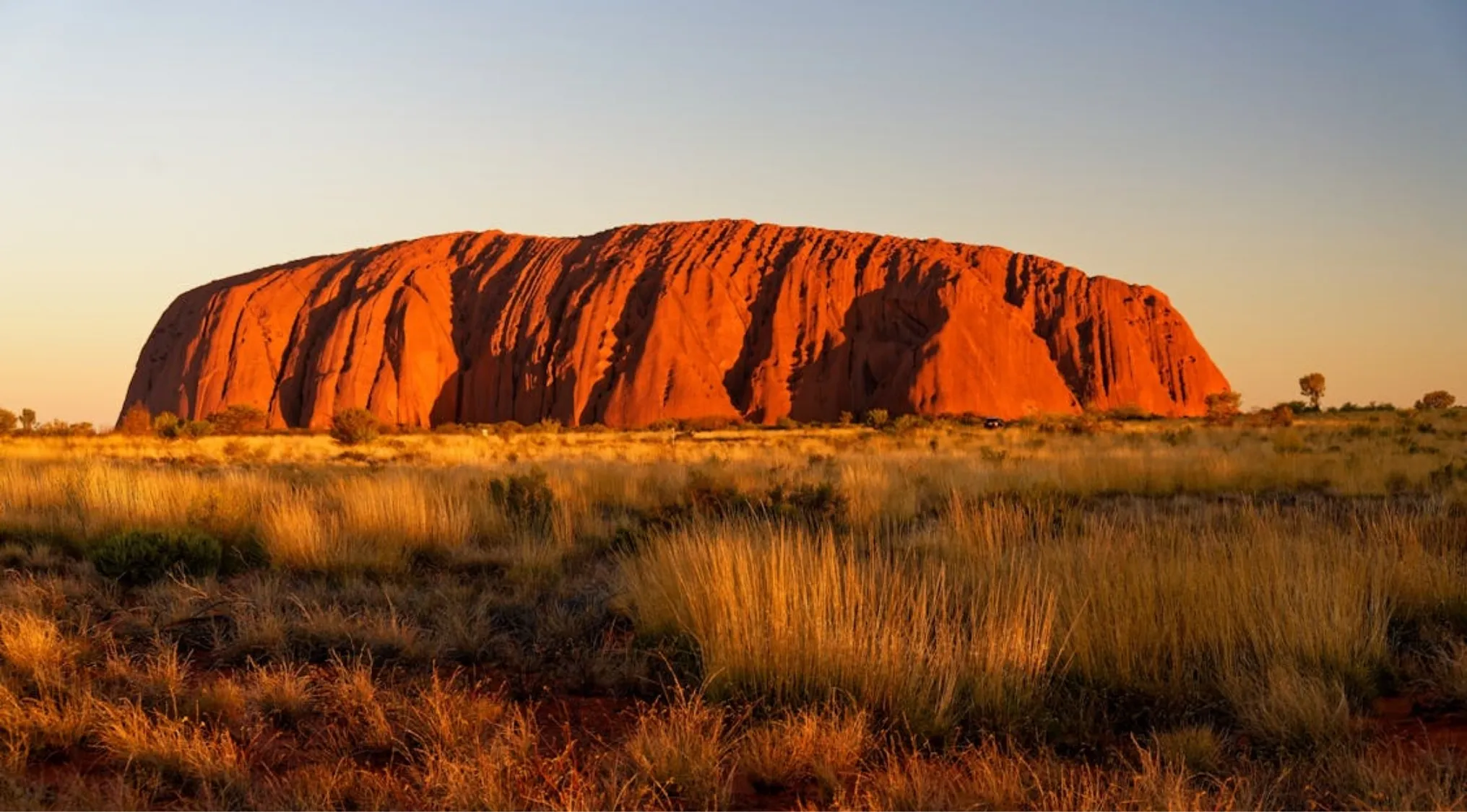 General Knowledge question: Uluru, a massive sandstone monolith in Australia's Red Center, glowing orange at sunset.
