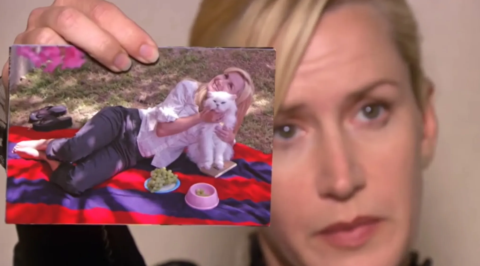 Angela from The Office holds a photo of her with her white cat. Test your knowledge with The Office Quiz!