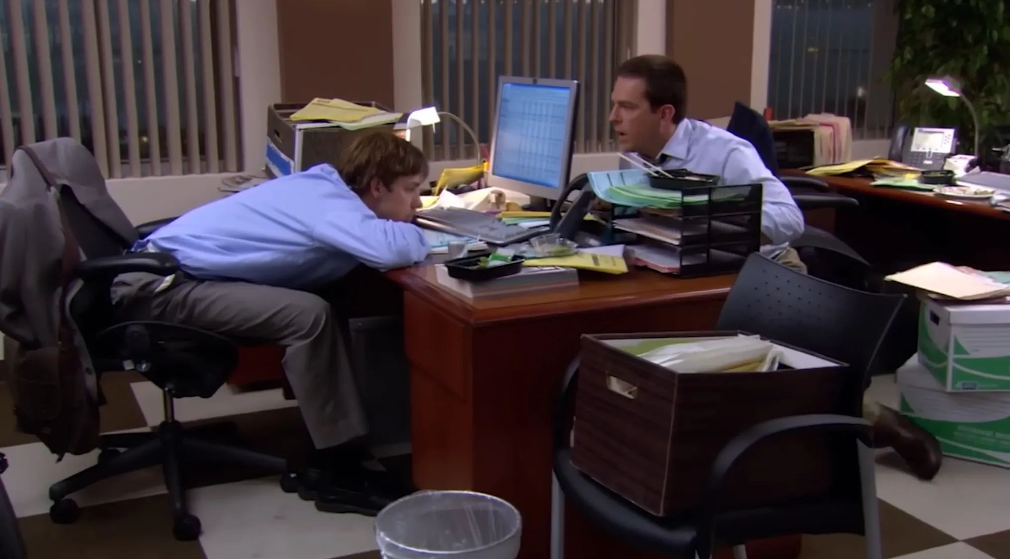 Jim resting on his desk, while Andy looks at him. The Office quiz answer related to Jim's nickname.
