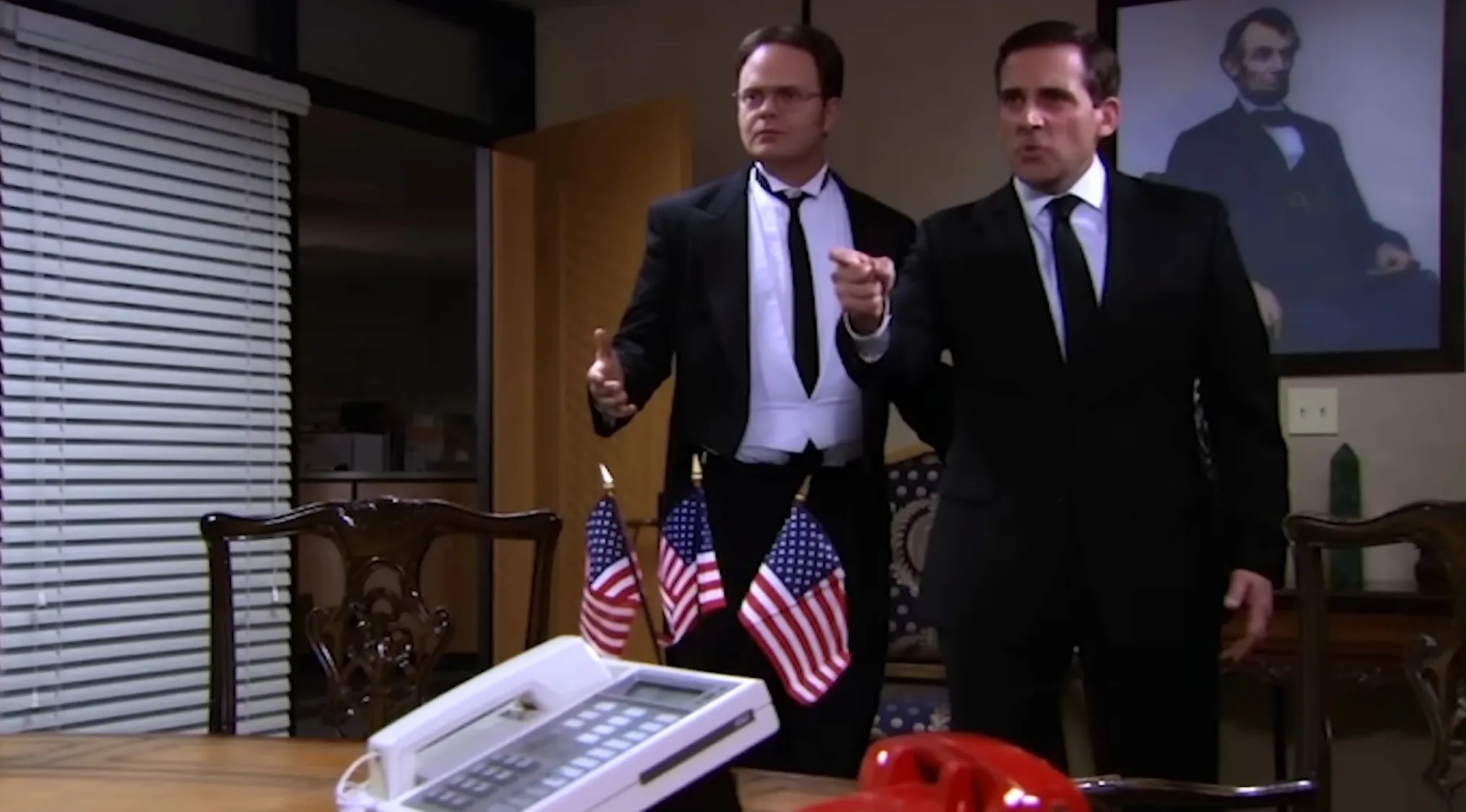 The Office Quiz: Michael Scott and Dwight Schrute in black suits standing behind a desk with American flags.
