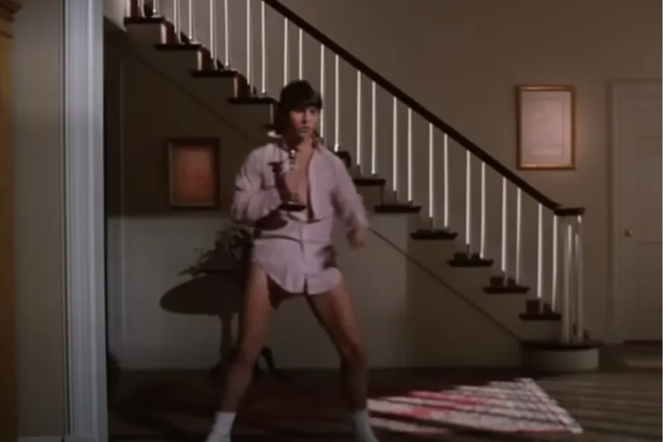 Tom Cruise in Risky Business, dancing in a pink shirt, underwear, and white socks in a living room.