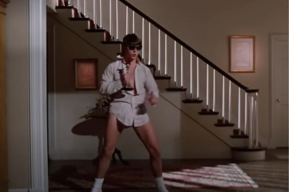 Tom Cruise in Risky Business, dancing in sunglasses, an unbuttoned shirt, and white socks, holding a trophy.
