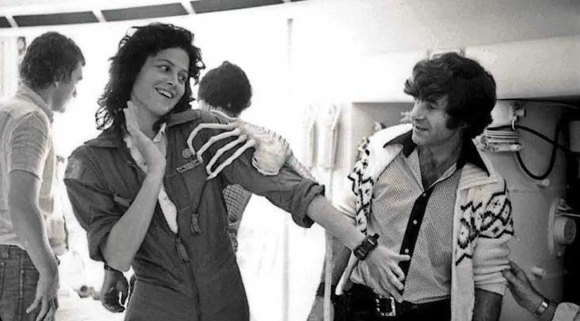 Guess The Movie: Sigourney Weaver smiling on a BTS movie set, with a skeleton prop on her shoulder.