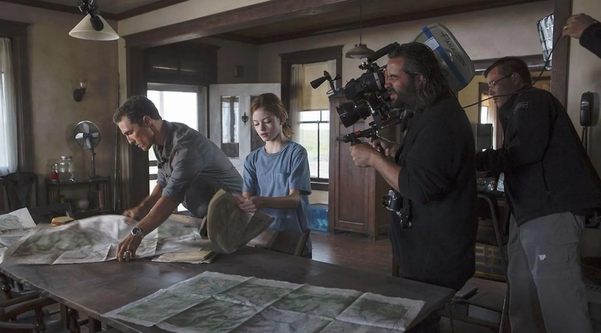 Guess The Movie from a BTS image showing Matthew McConaughey and a girl studying maps, filmed by a crew.