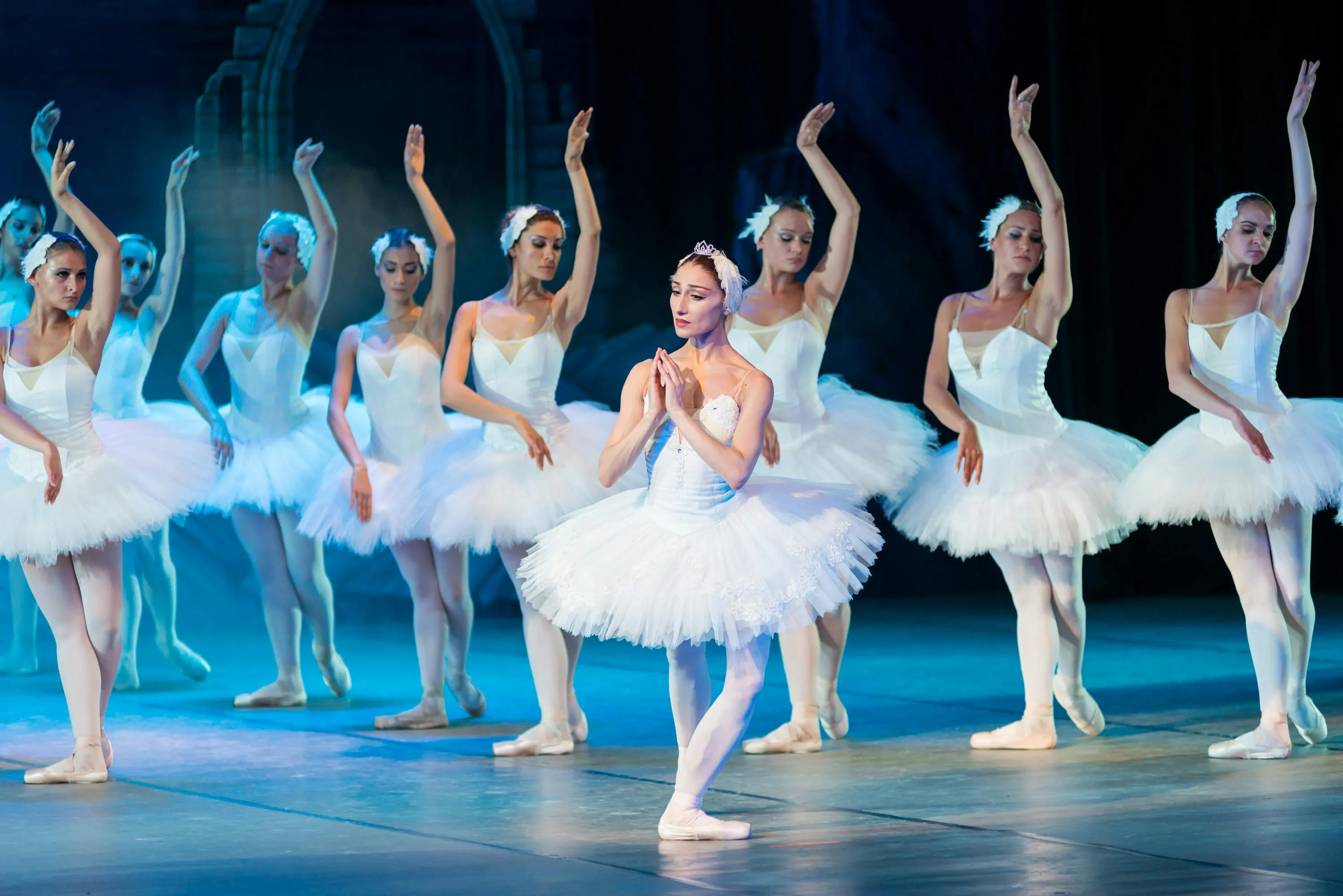 Ballerinas in white tutus performing, posing gracefully on stage, perfect for General Knowledge trivia about famous ballet composers.
