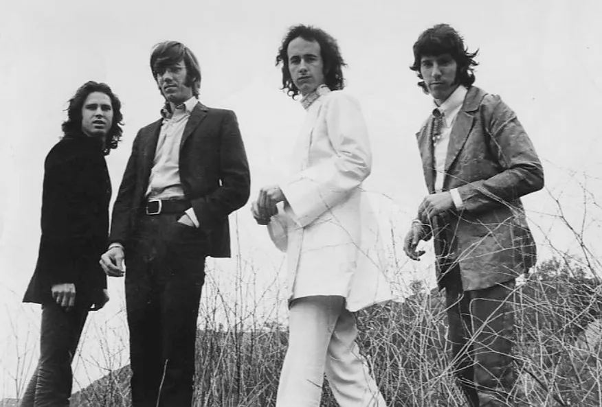 Black and white photo of The Doors, four men in jackets, standing in a field of thorny bushes.
