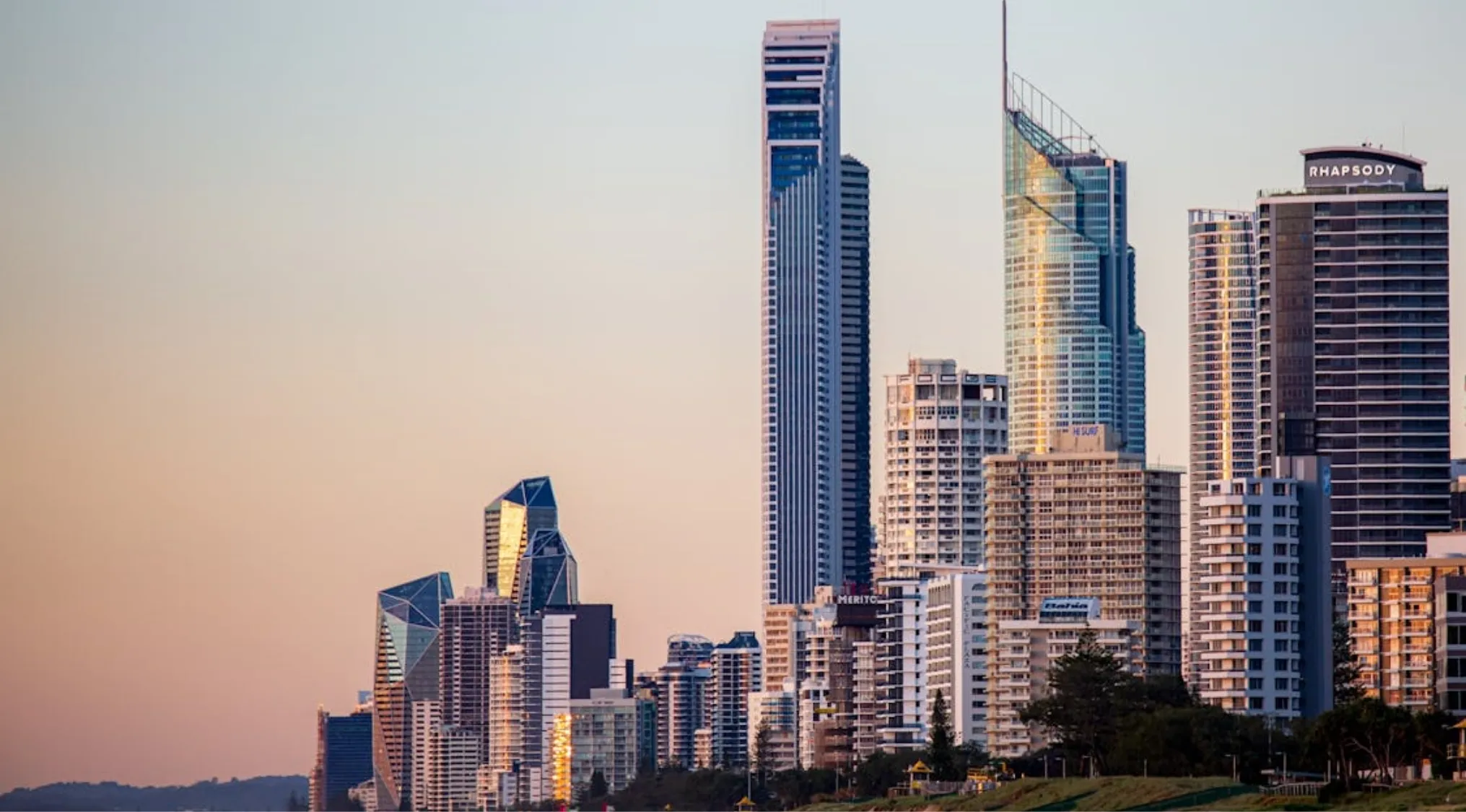 Modern skyscrapers gleaming under a soft sky, reflecting light. This city image relates to Australian Citizenship.