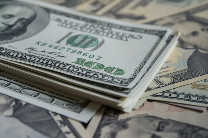 Close-up of stacked hundred-dollar bills representing betrayal and shock in acts of being a good person.